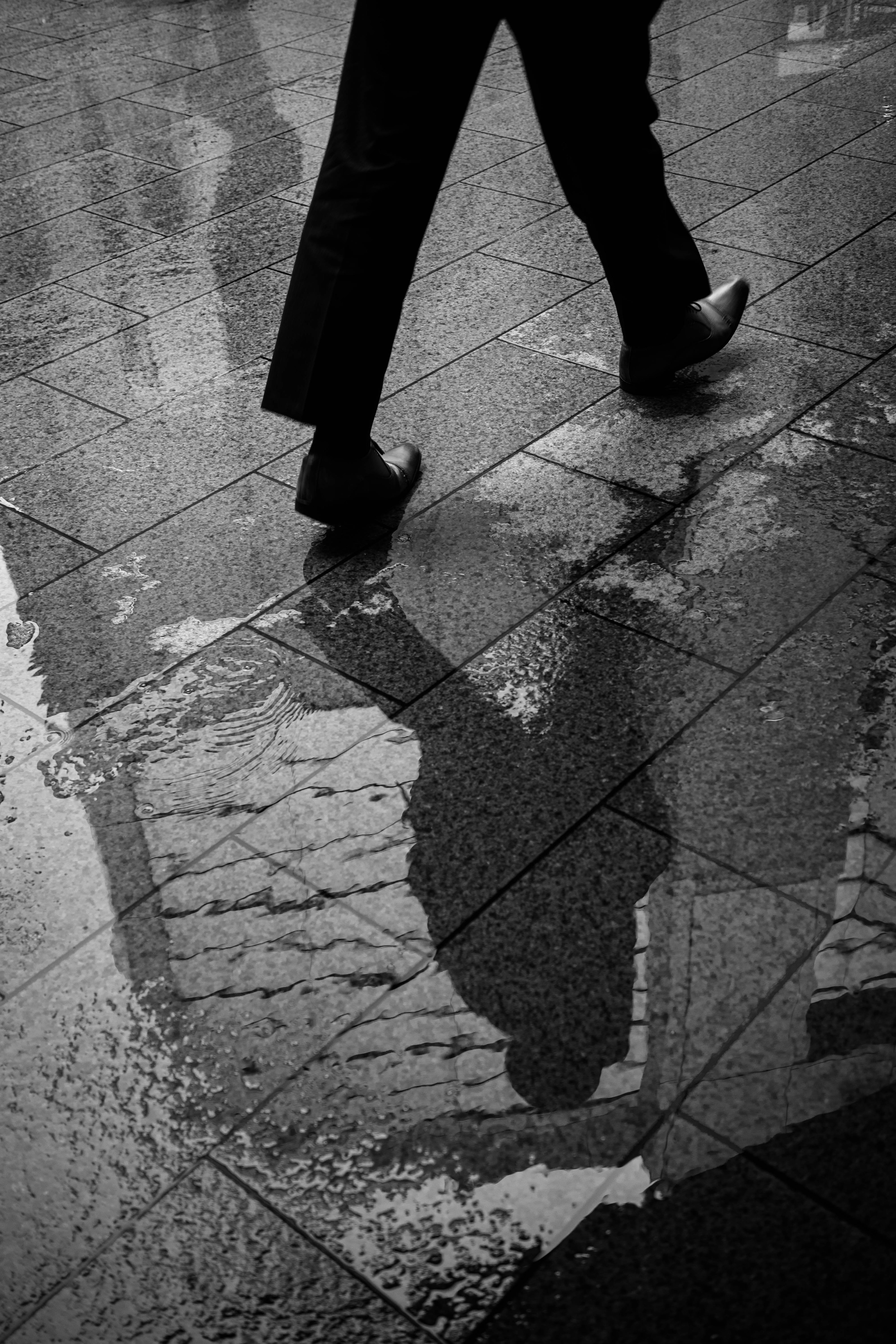 Réflexion d'une personne marchant dans une flaque d'eau avec un costume sombre