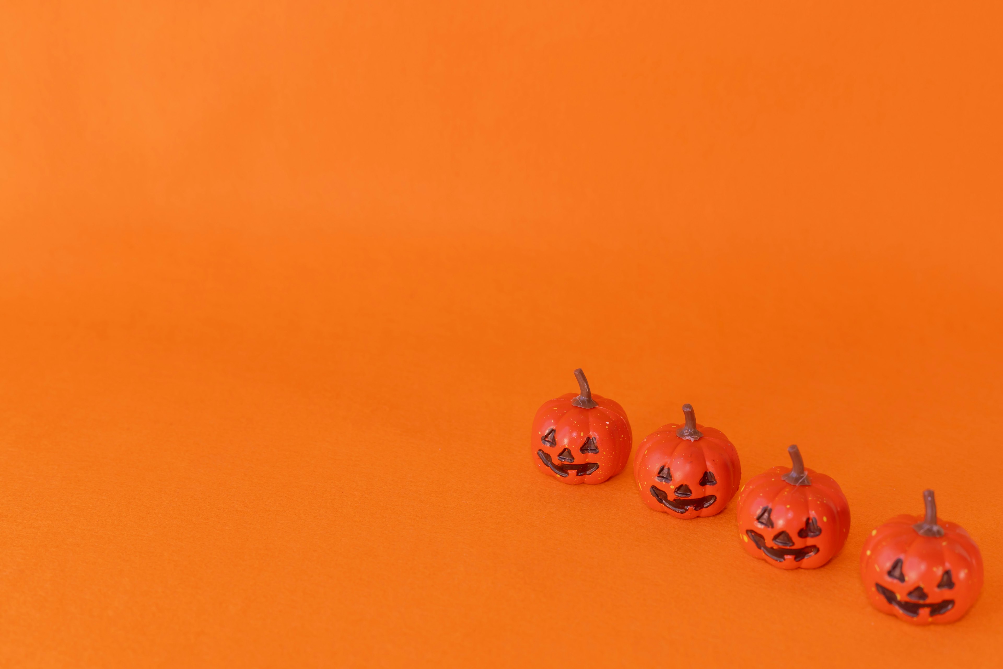 Miniatur labu jack-o'-lantern tersenyum di latar belakang oranye