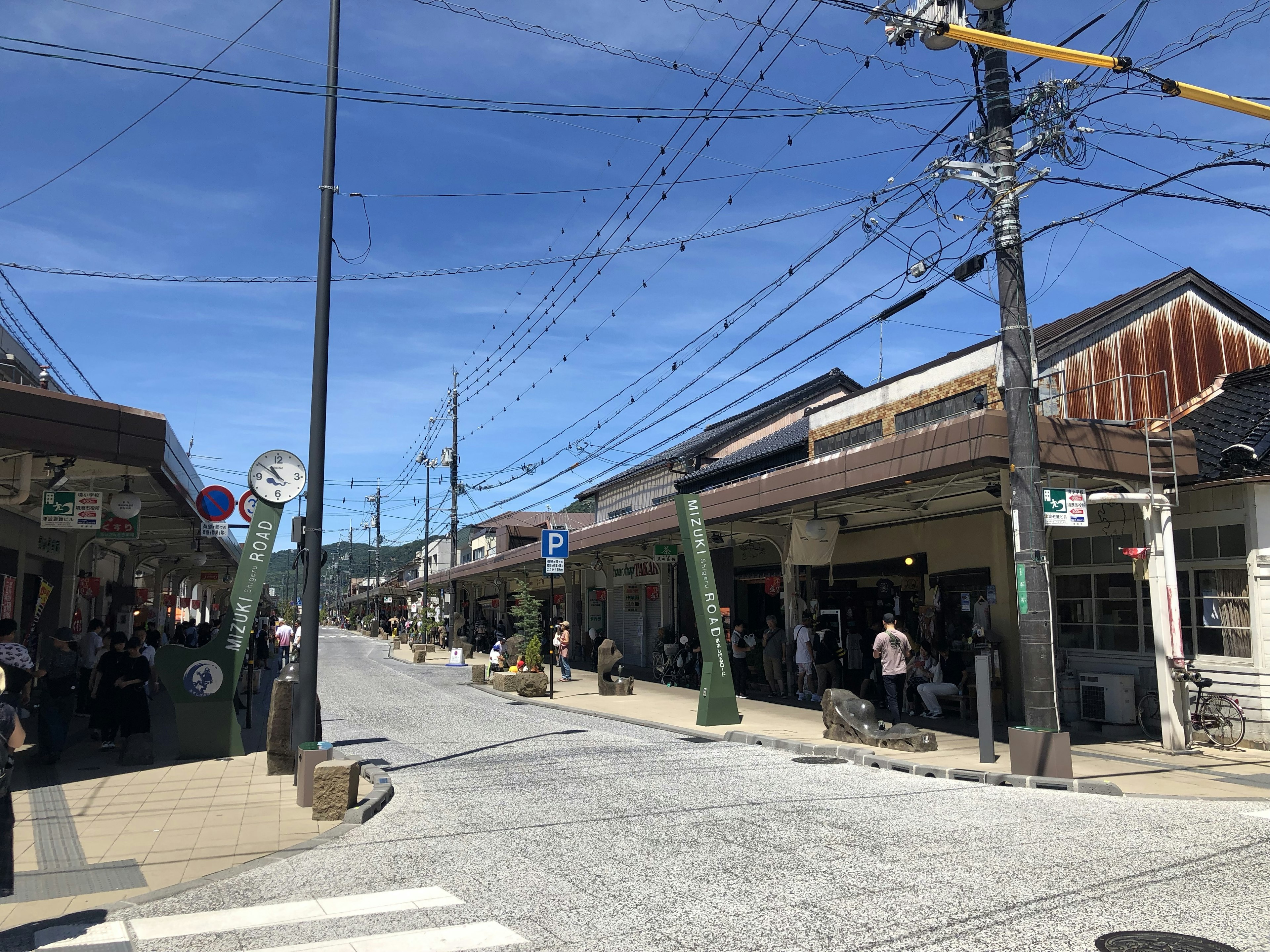 Vue de rue d'un quartier commerçant sous un ciel bleu avec des gens et des bâtiments traditionnels