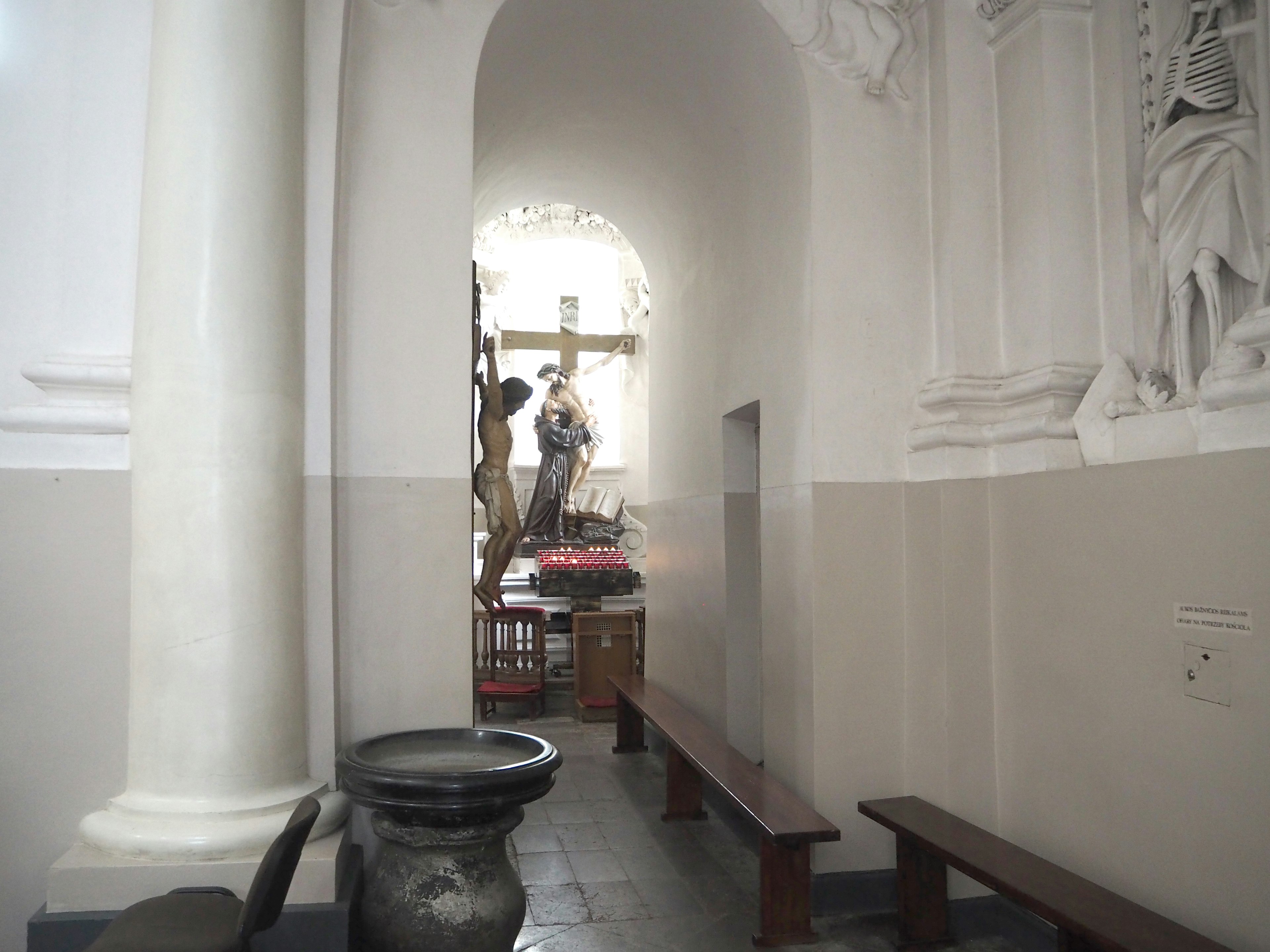 Quiet hallway inside a church with visible cross and saint sculptures