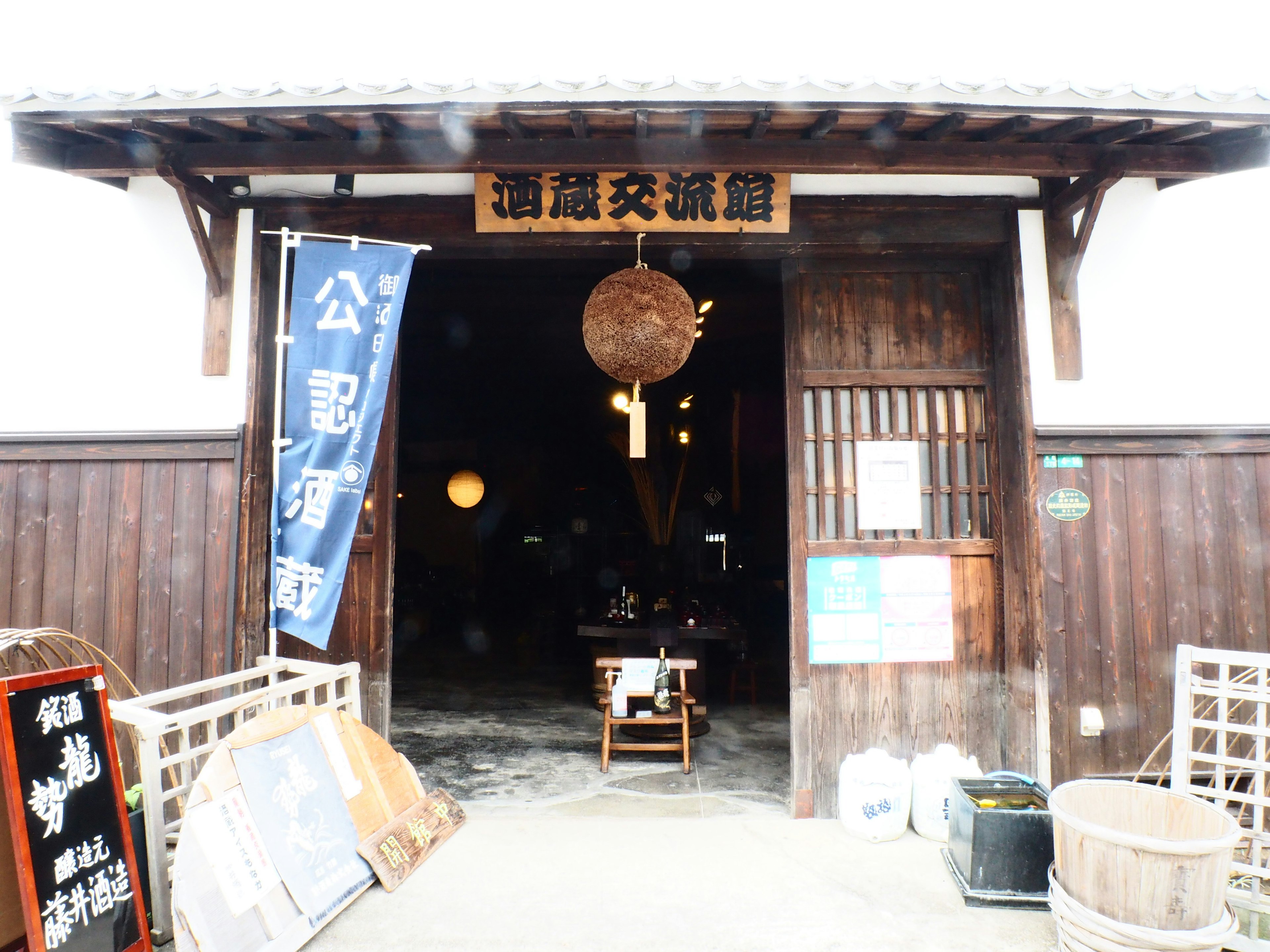 Entrance of a traditional Japanese sake brewery featuring wooden doors and warm lighting