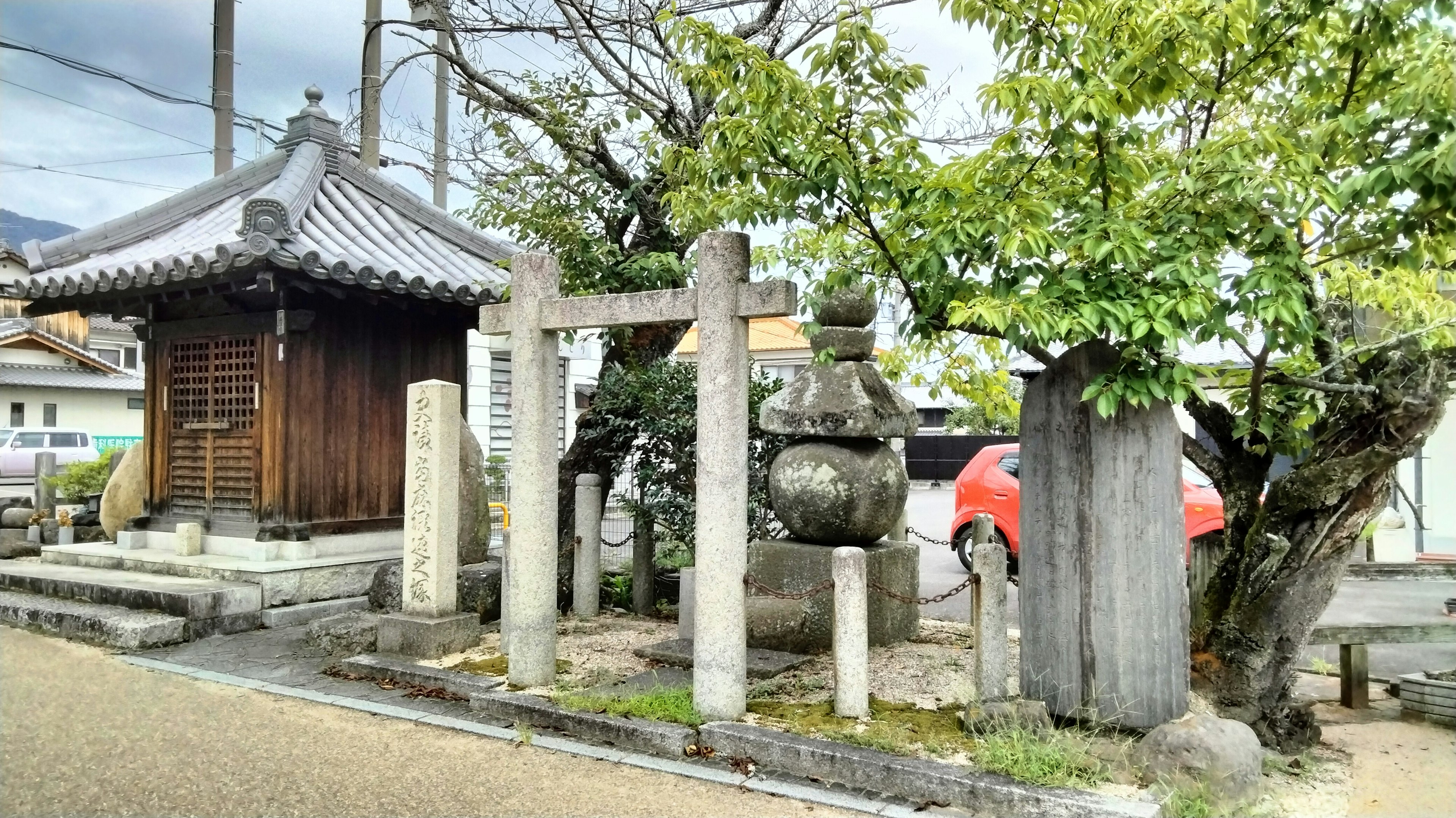 Un santuario tradizionale con un torii in pietra e alberi circostanti