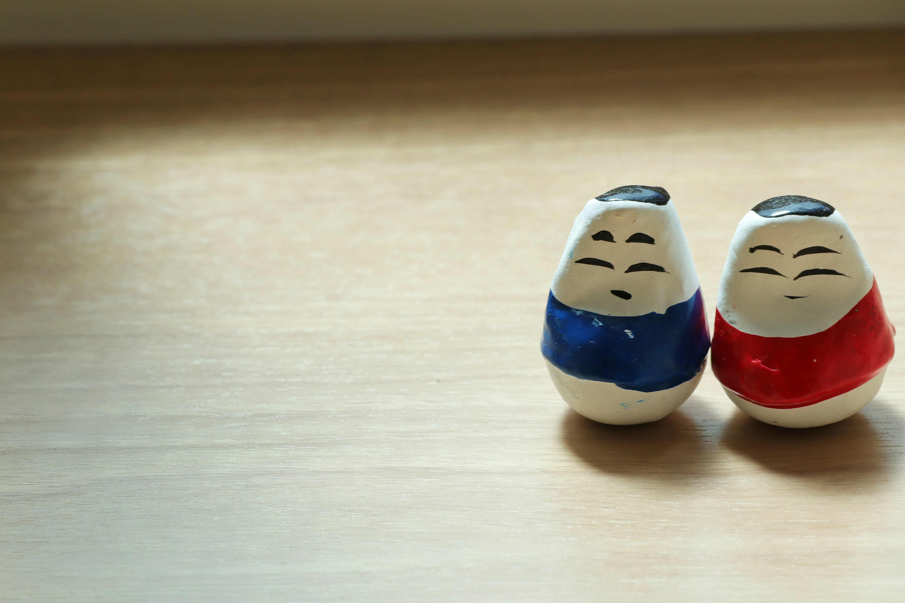 Two small ceramic figures dressed in red and blue outfits