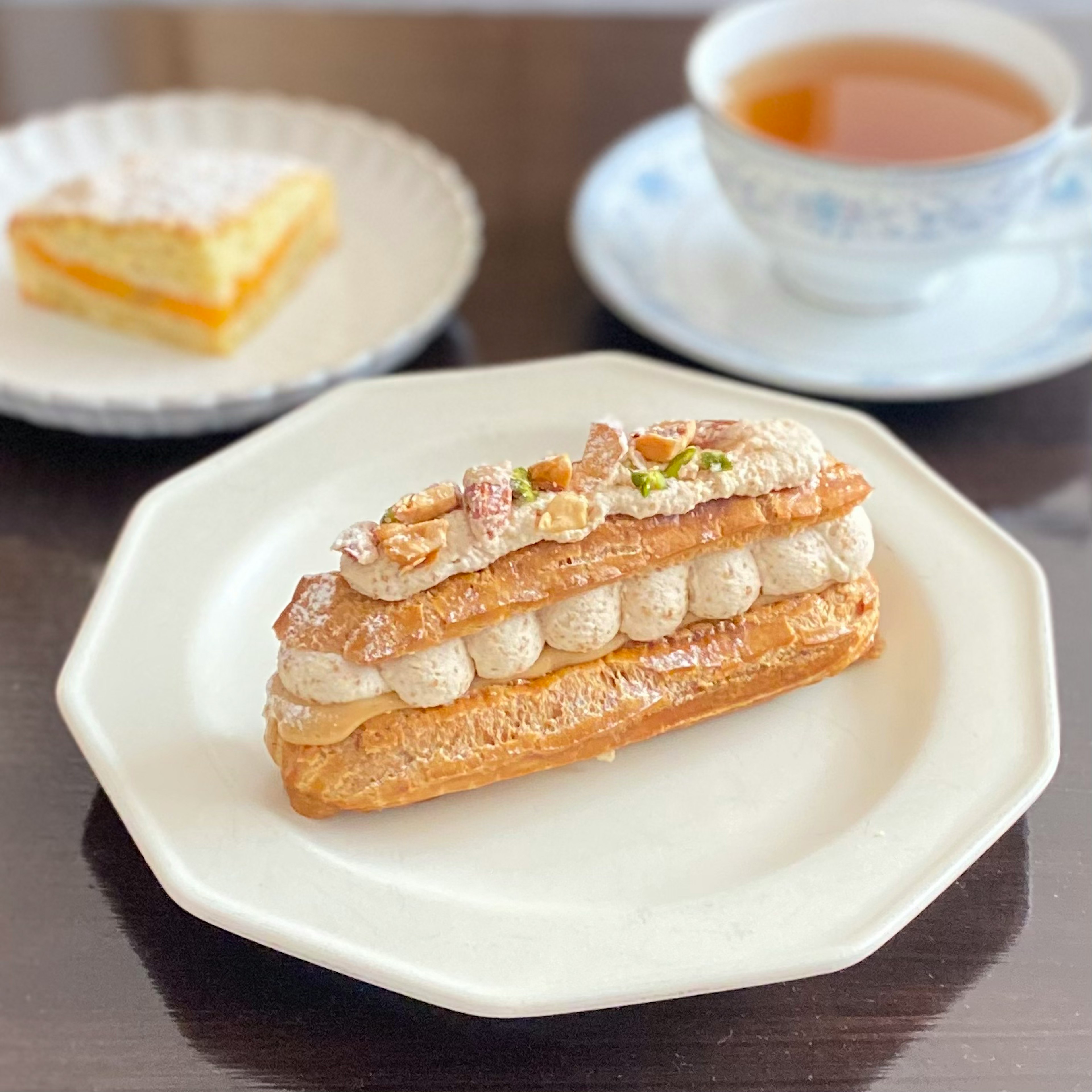 Cream-filled éclair served with tea and a slice of cake