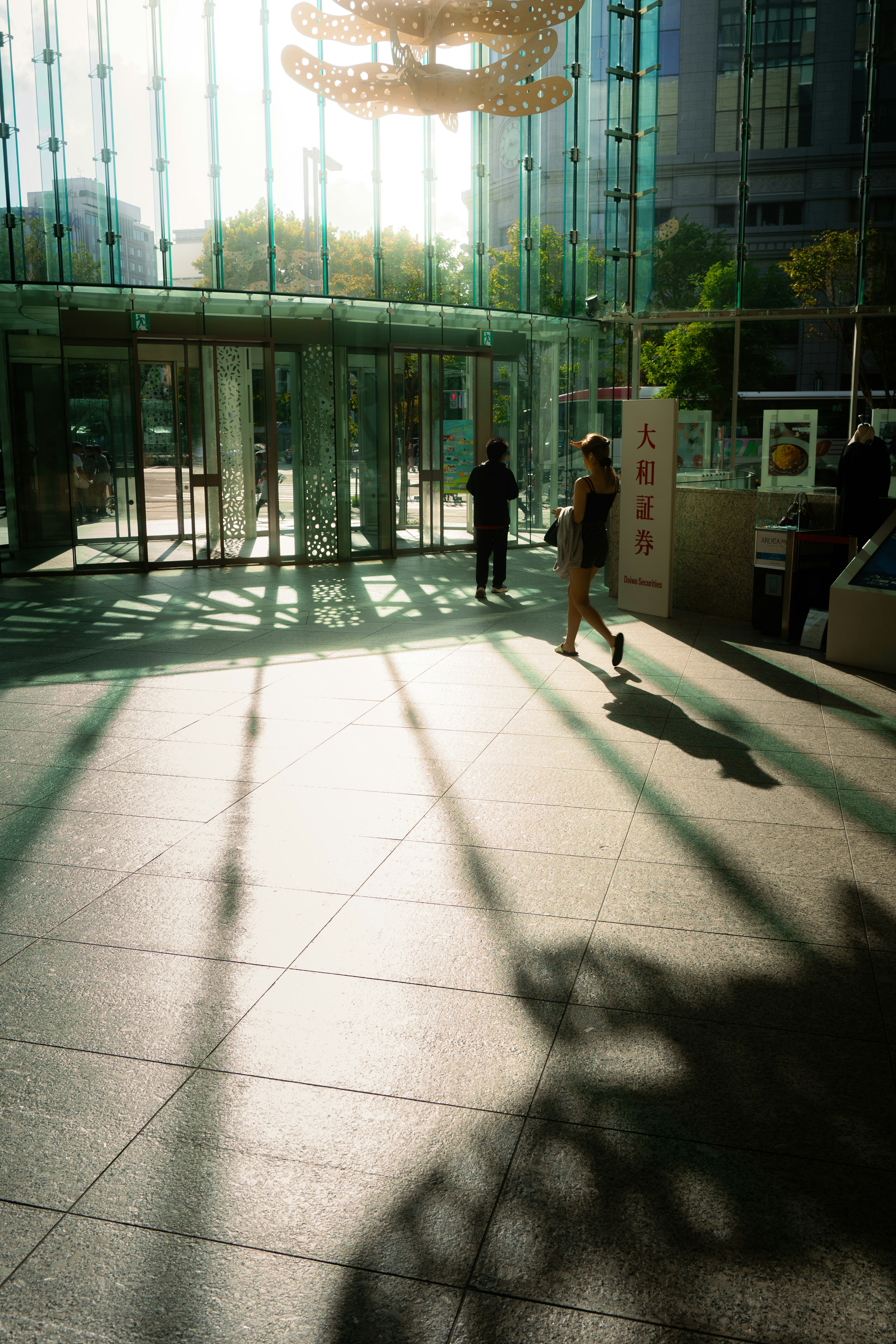 Una mujer caminando en una entrada iluminada con sombras en el suelo