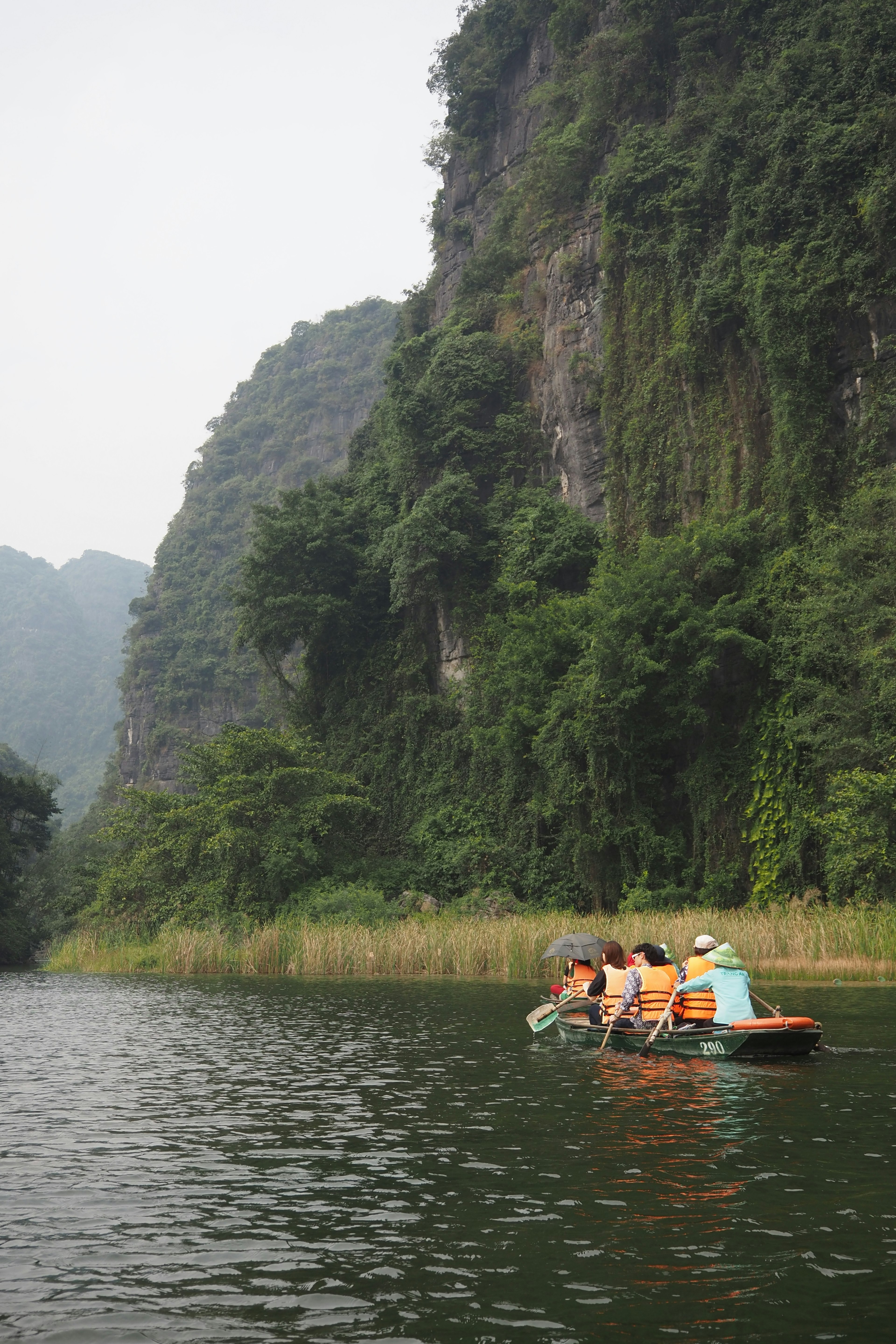 People in a boat on a serene river surrounded by lush green mountains