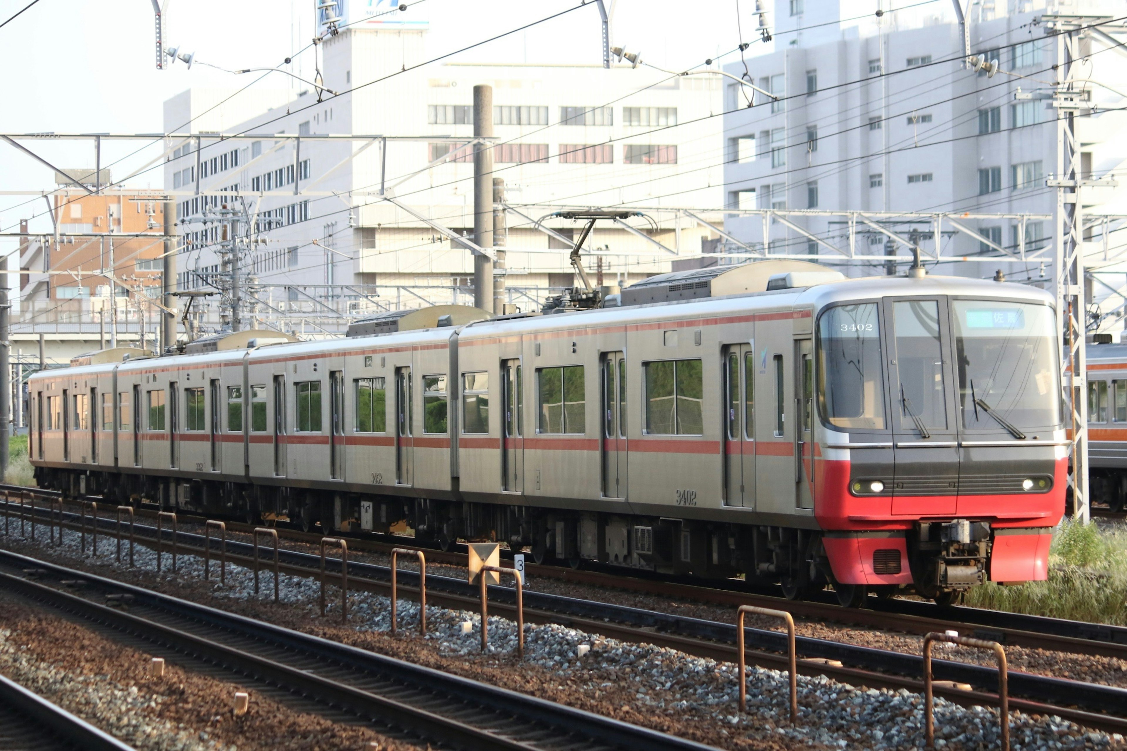 Silver train with red stripe parked on the tracks