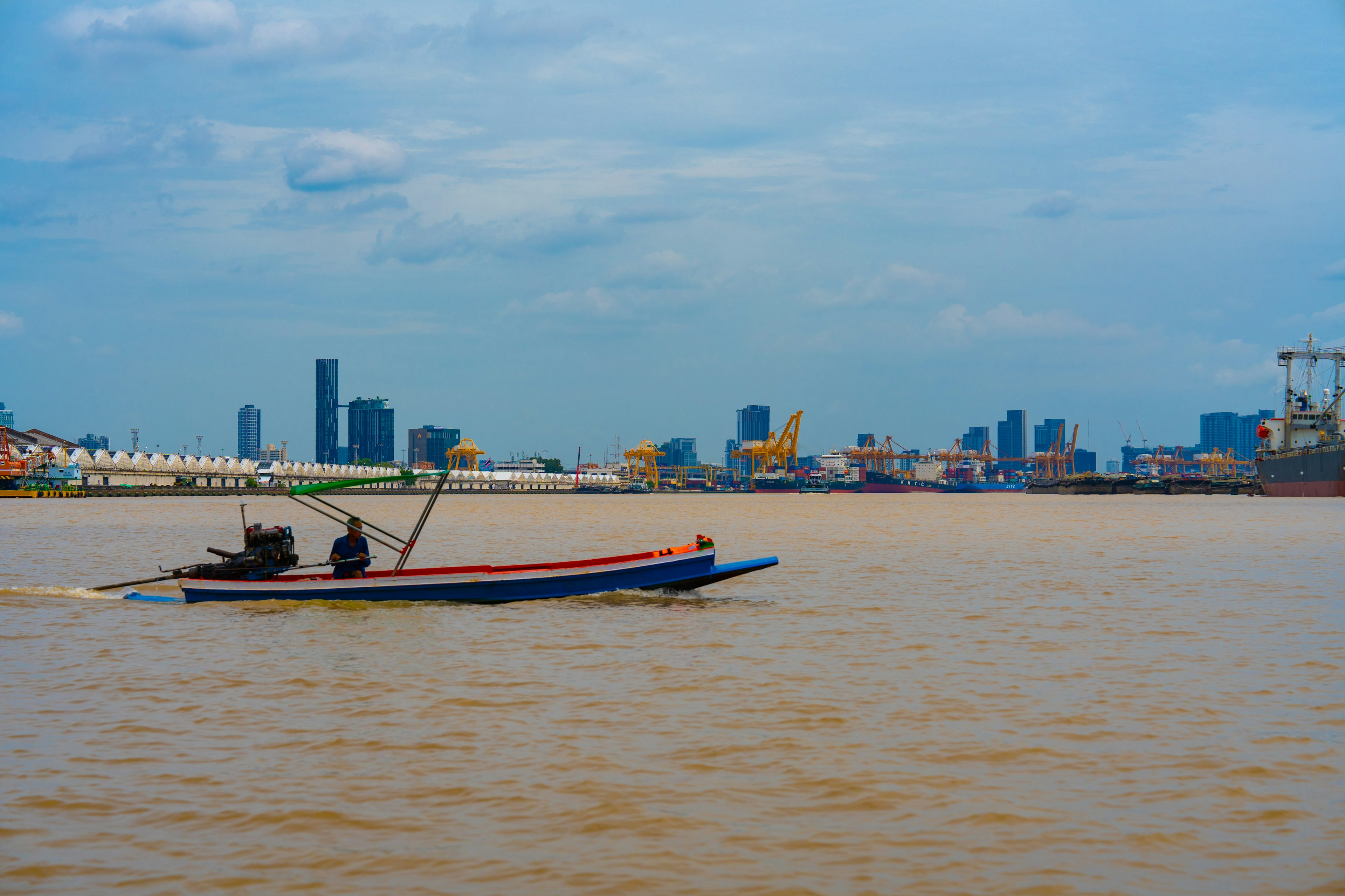 Una piccola barca che naviga su un fiume con lo skyline di una città sullo sfondo