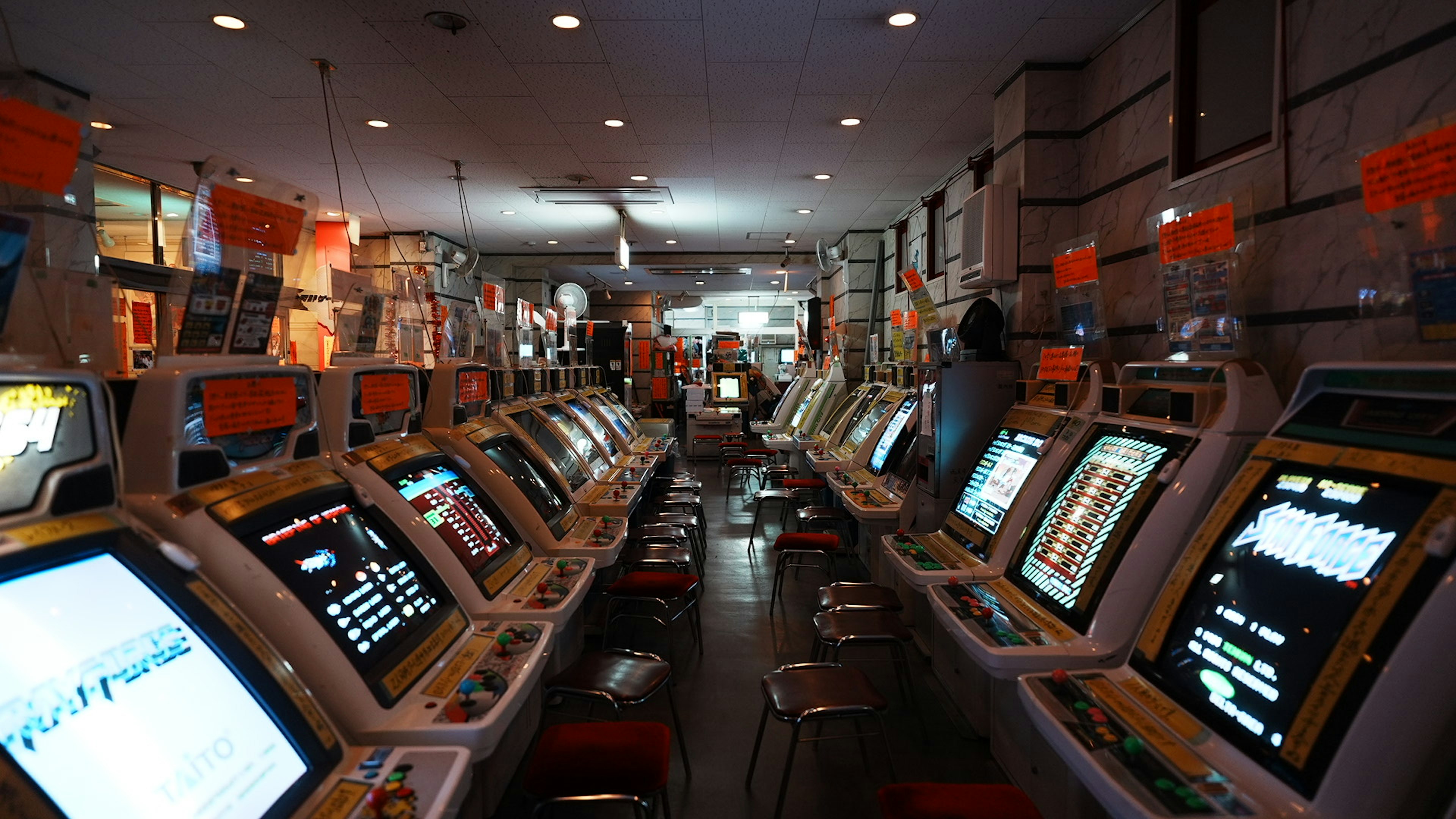 Interior arcade dengan deretan mesin slot layar terang