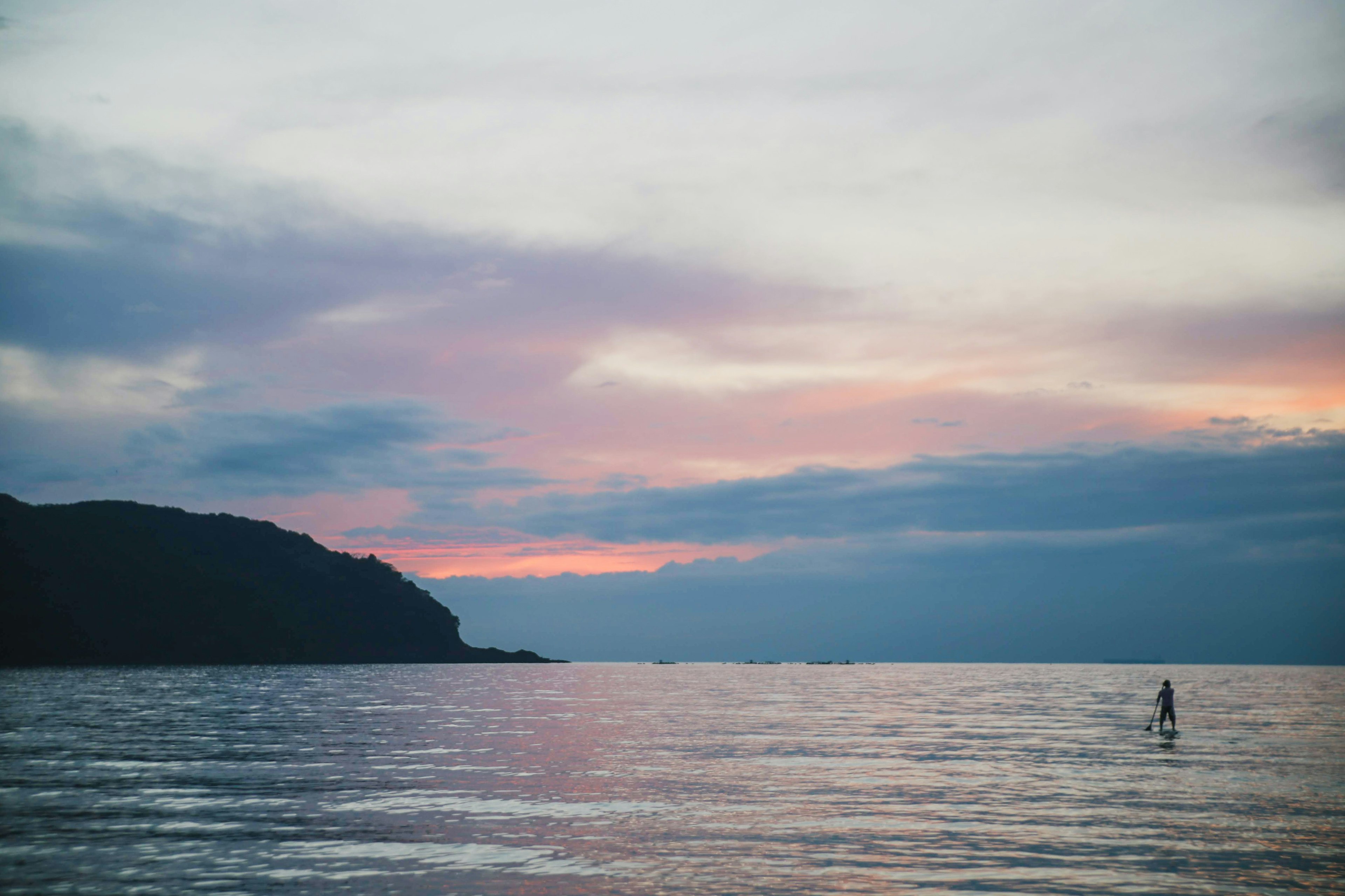 海と夕焼けの景色に立つサーフィンをする人