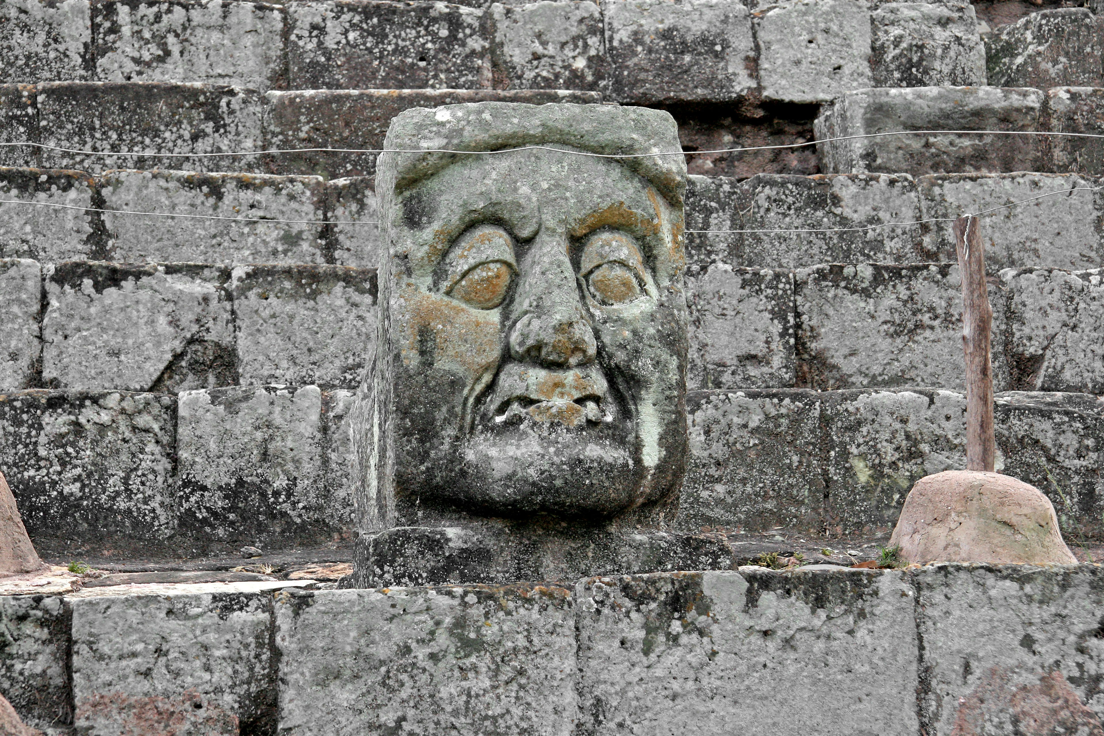 Antigua pared de piedra con una escultura de rostro tallada