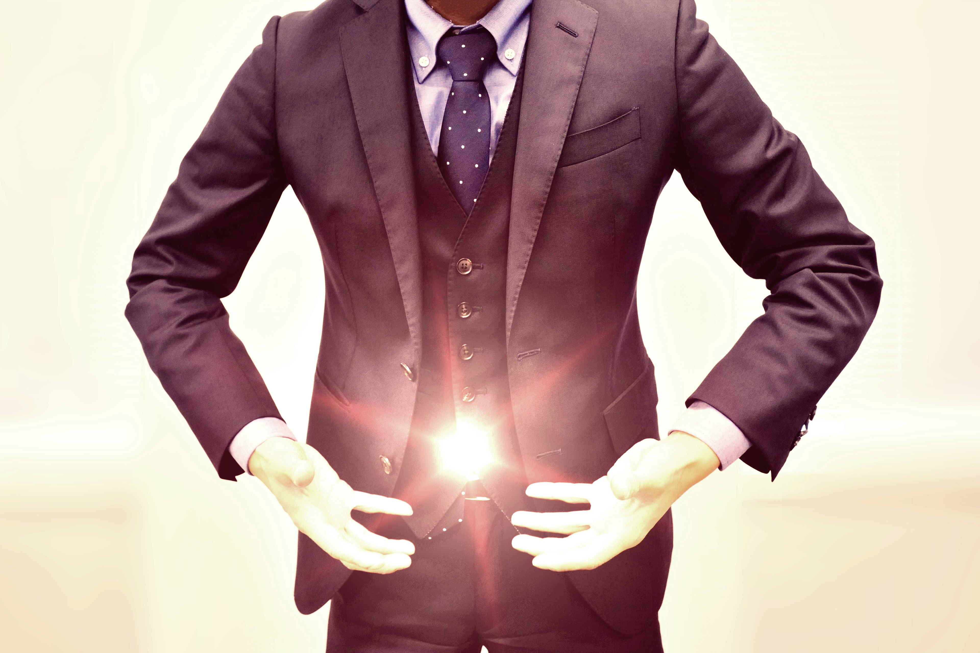 A man in a suit pointing at a glowing center with his hands