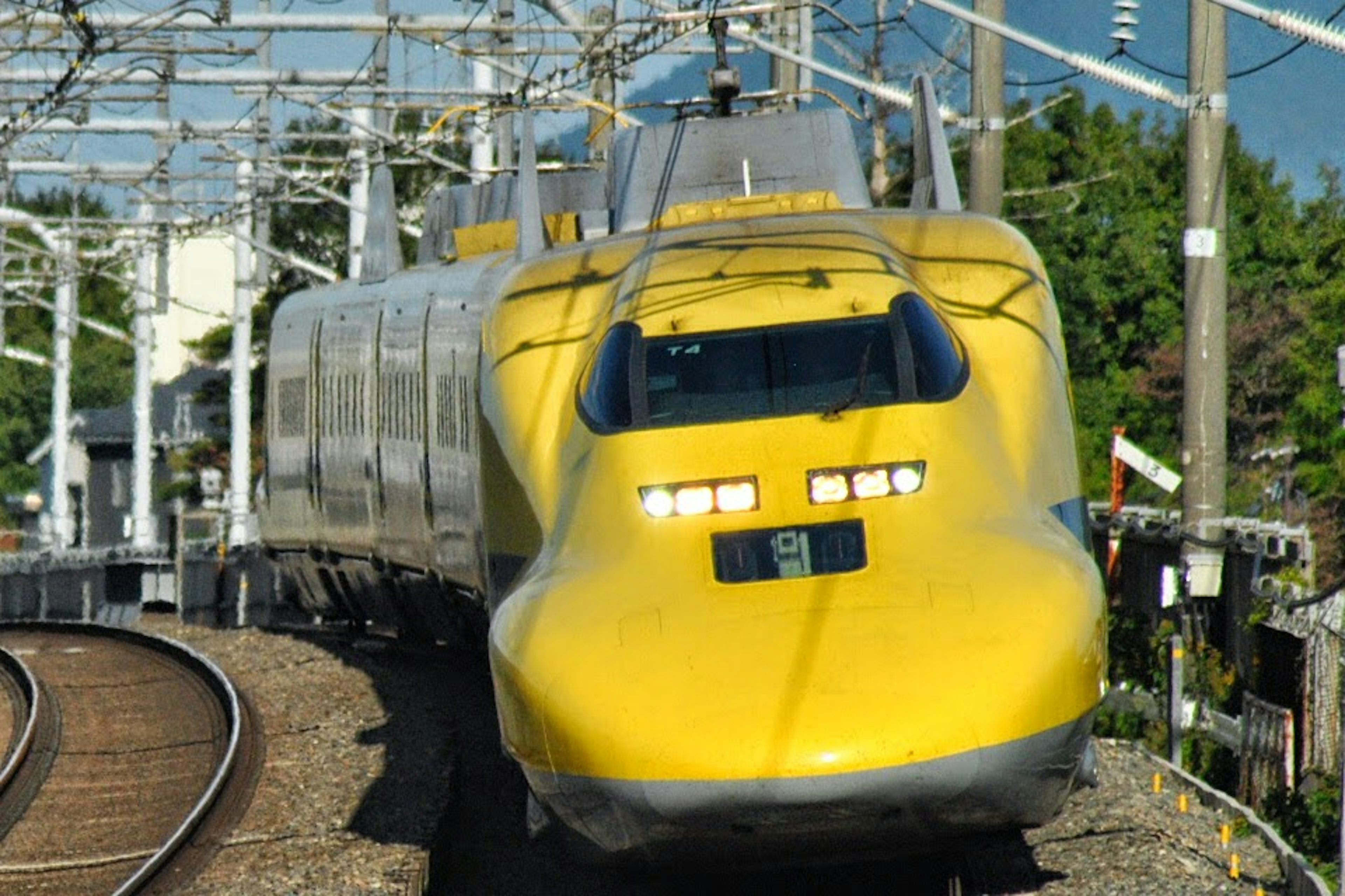 Kereta Shinkansen kuning mendekati tikungan