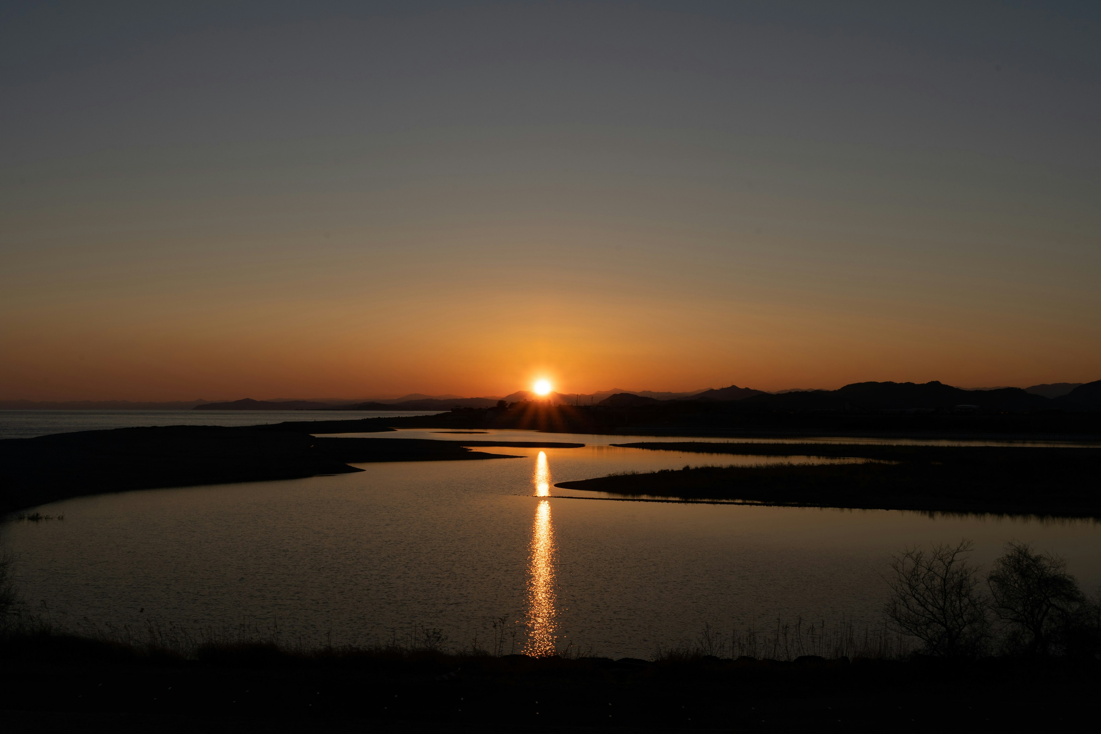 Sunset over a tranquil lake with the sun dipping below the horizon