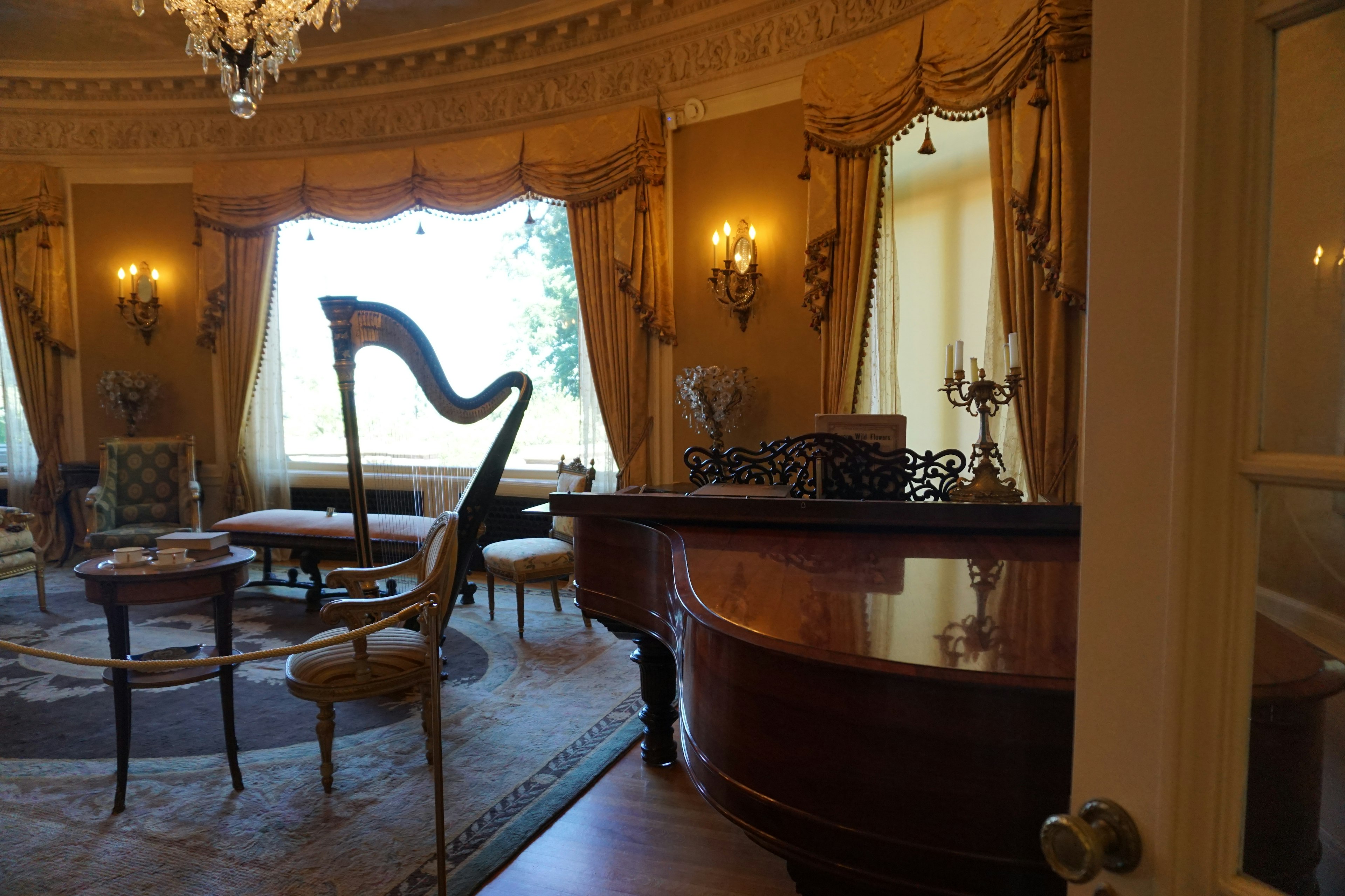 Elegant room featuring a harp and grand piano with natural light streaming through the windows