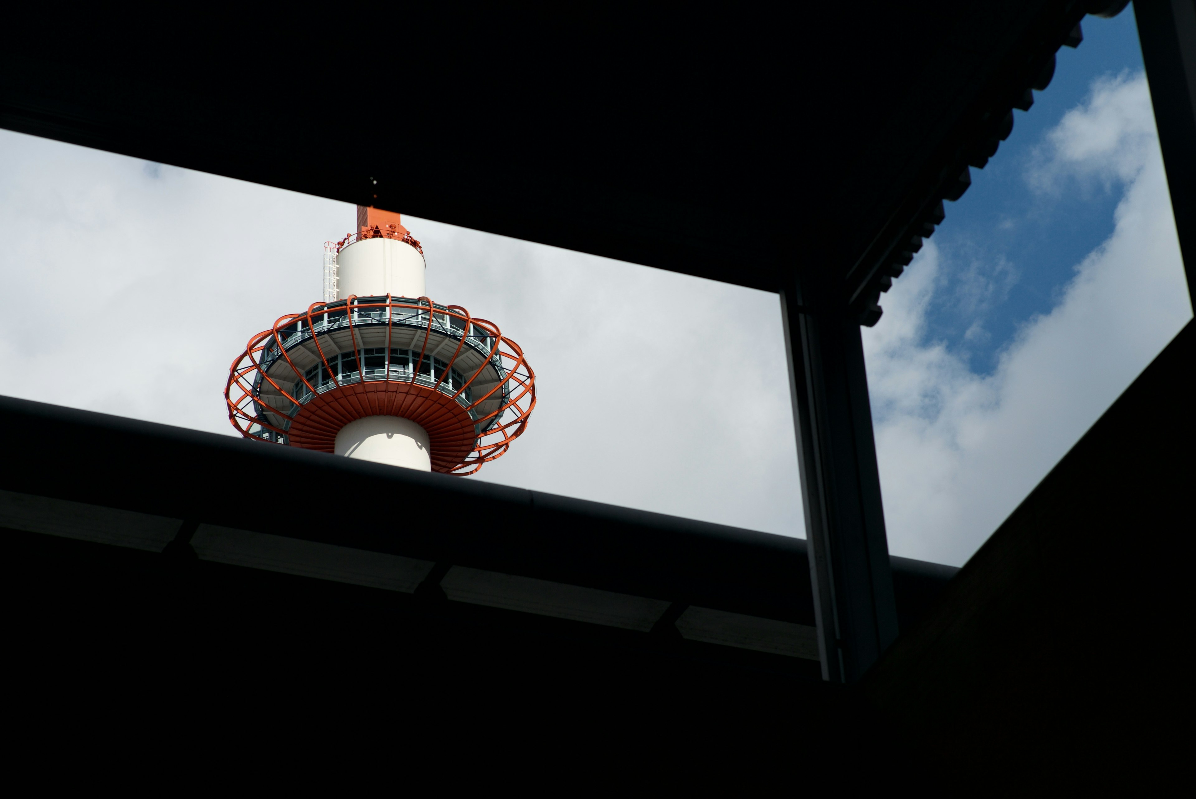 Silhouette of a tower against a blue sky framed by surrounding buildings