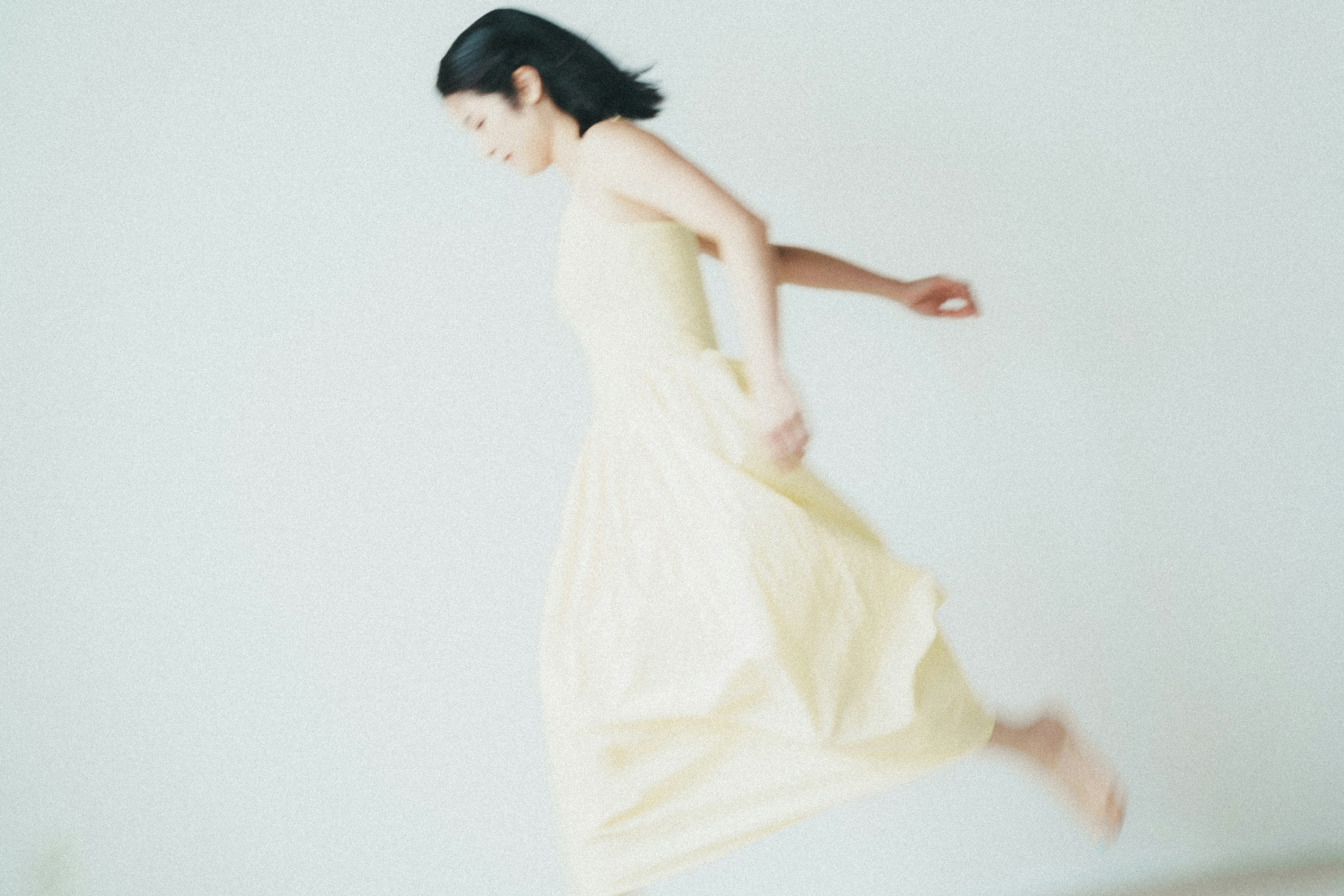 Una mujer con un vestido amarillo claro saltando con gracia