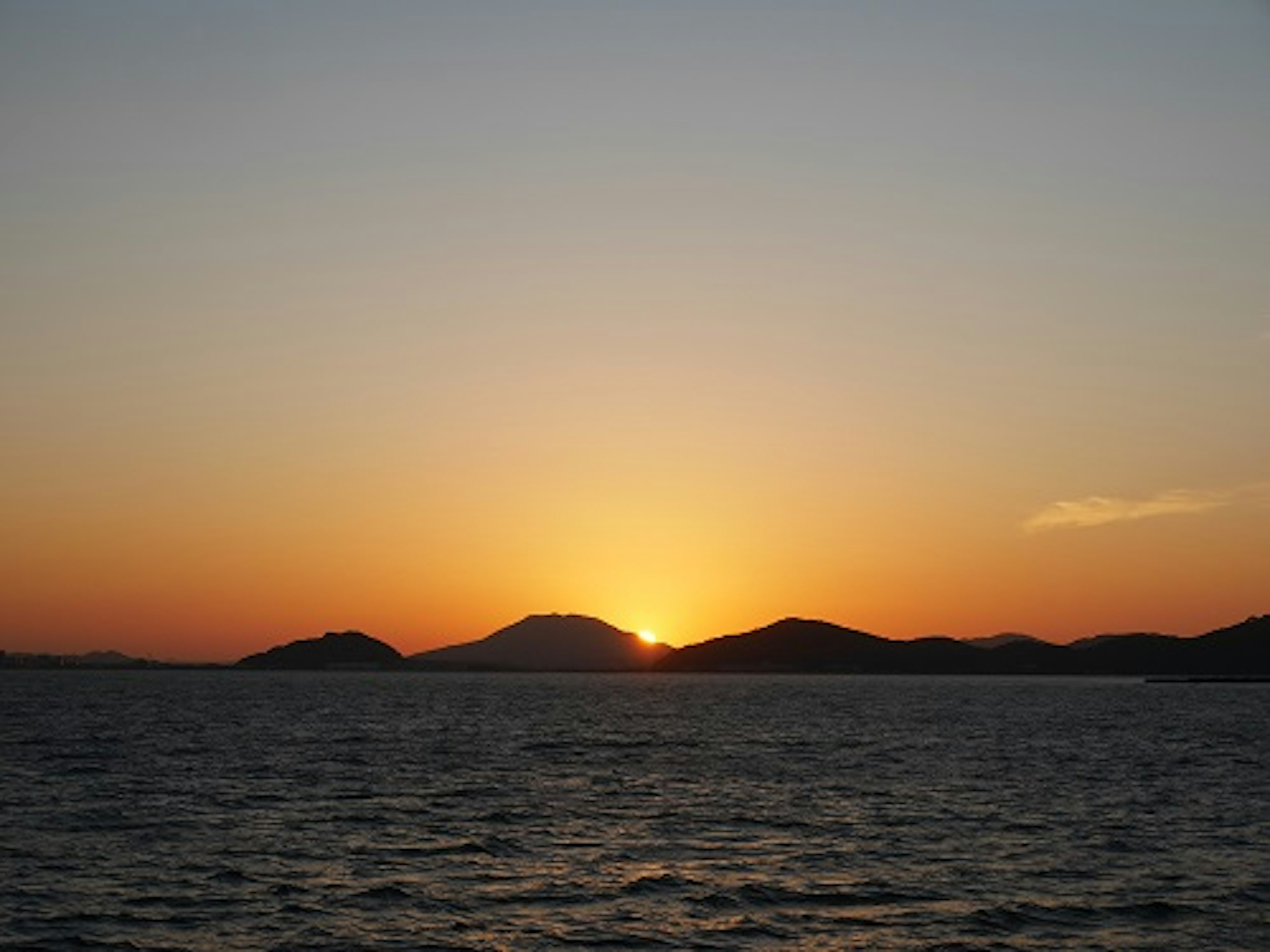 Paysage maritime magnifique avec le coucher de soleil derrière les montagnes