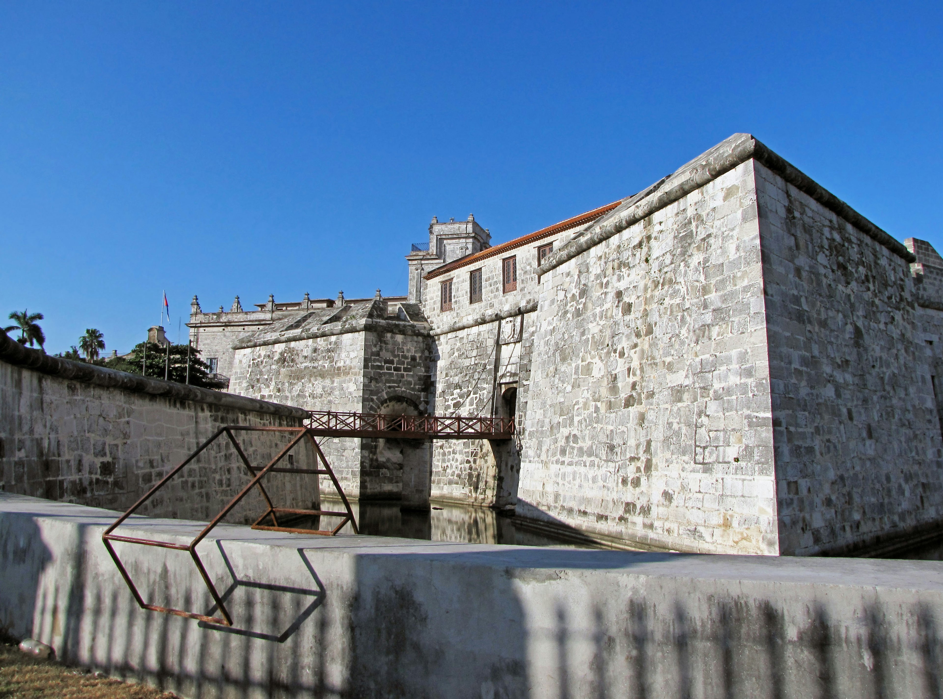 Vieux fort en pierre sous un ciel bleu avec une structure en métal au premier plan