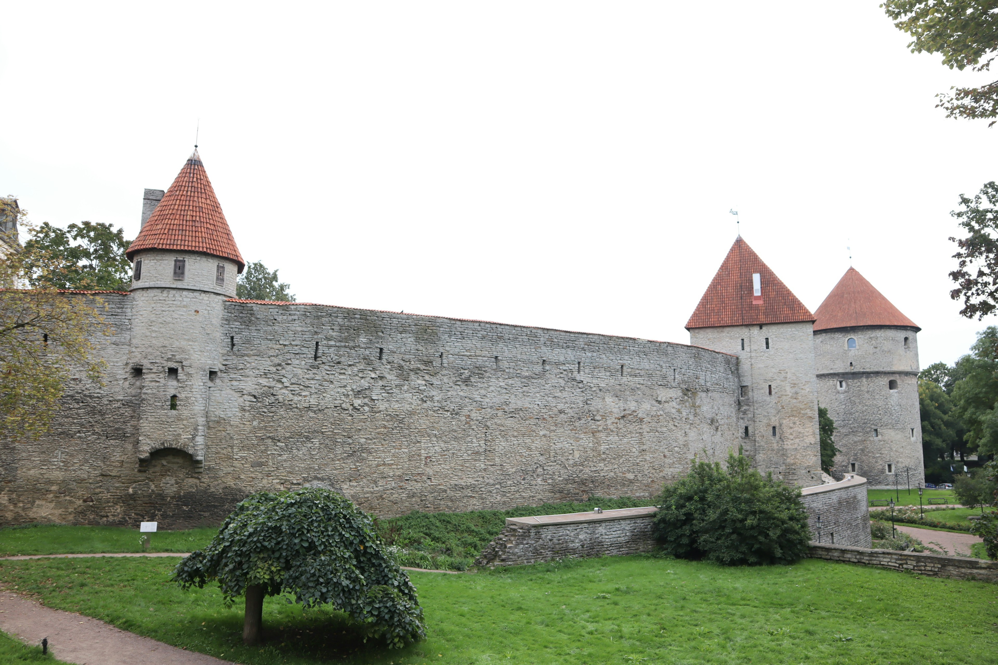 Medieval castle wall with towers in a green garden setting