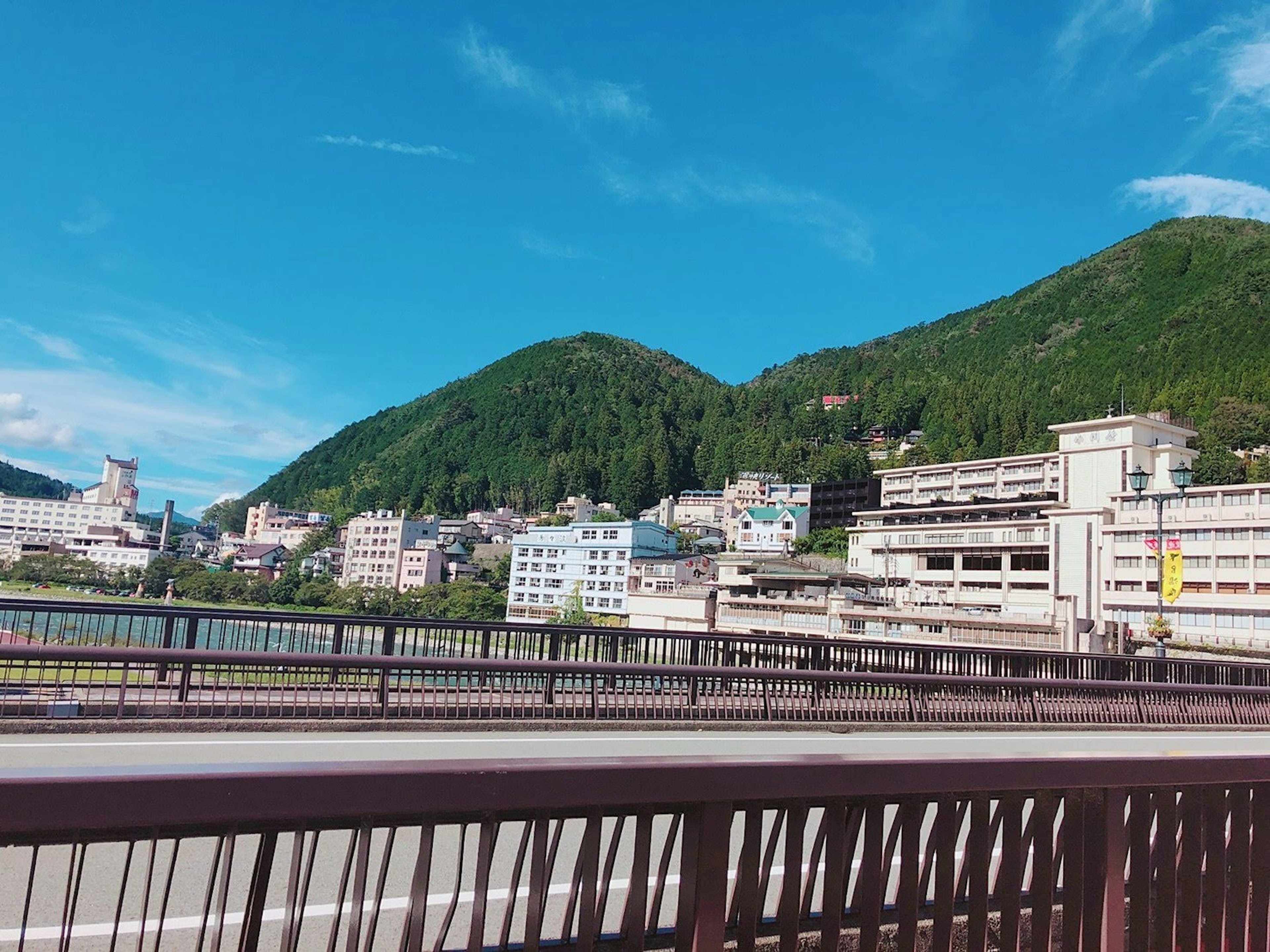 Malerscher Blick auf Berge und Stadt unter blauem Himmel von einer Brücke aus