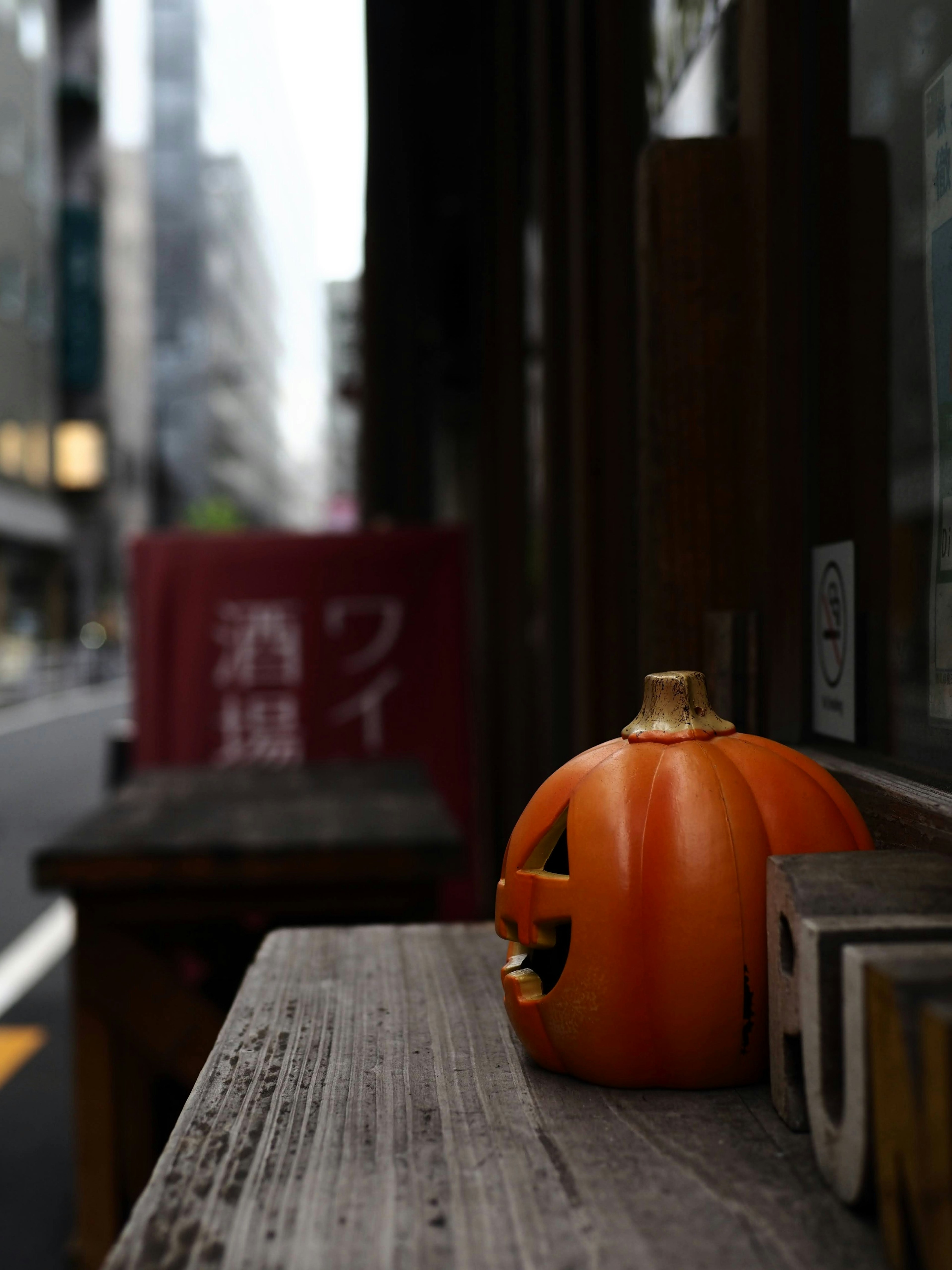 An orange jack-o'-lantern placed on a wooden table in a city street setting