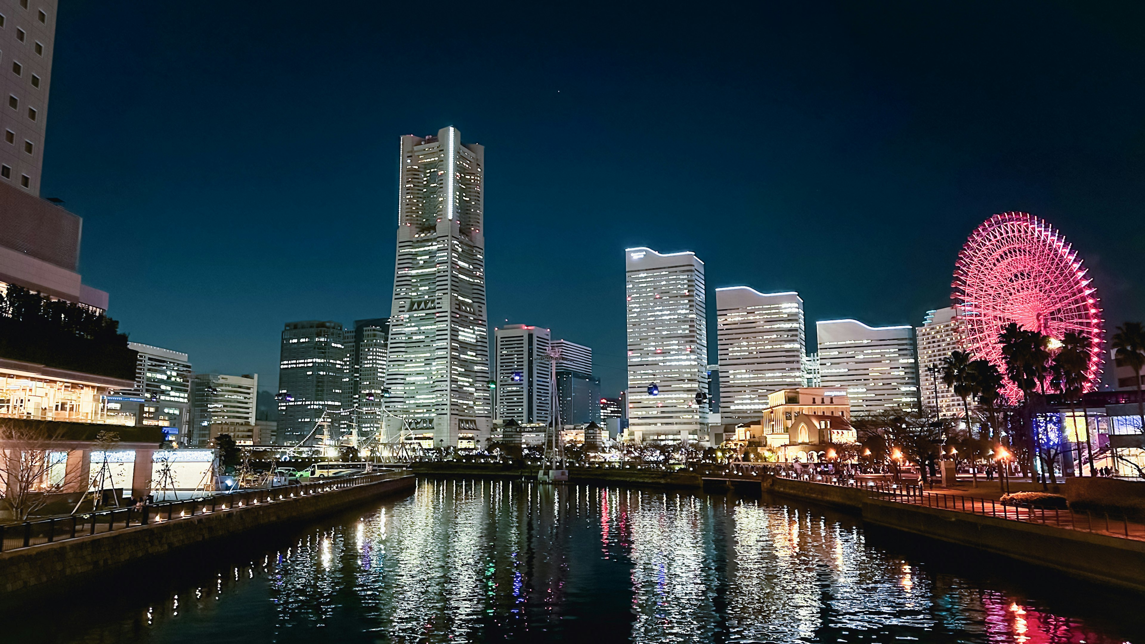 Pemandangan malam skyline Yokohama dengan pantulan di air dan roda ferris