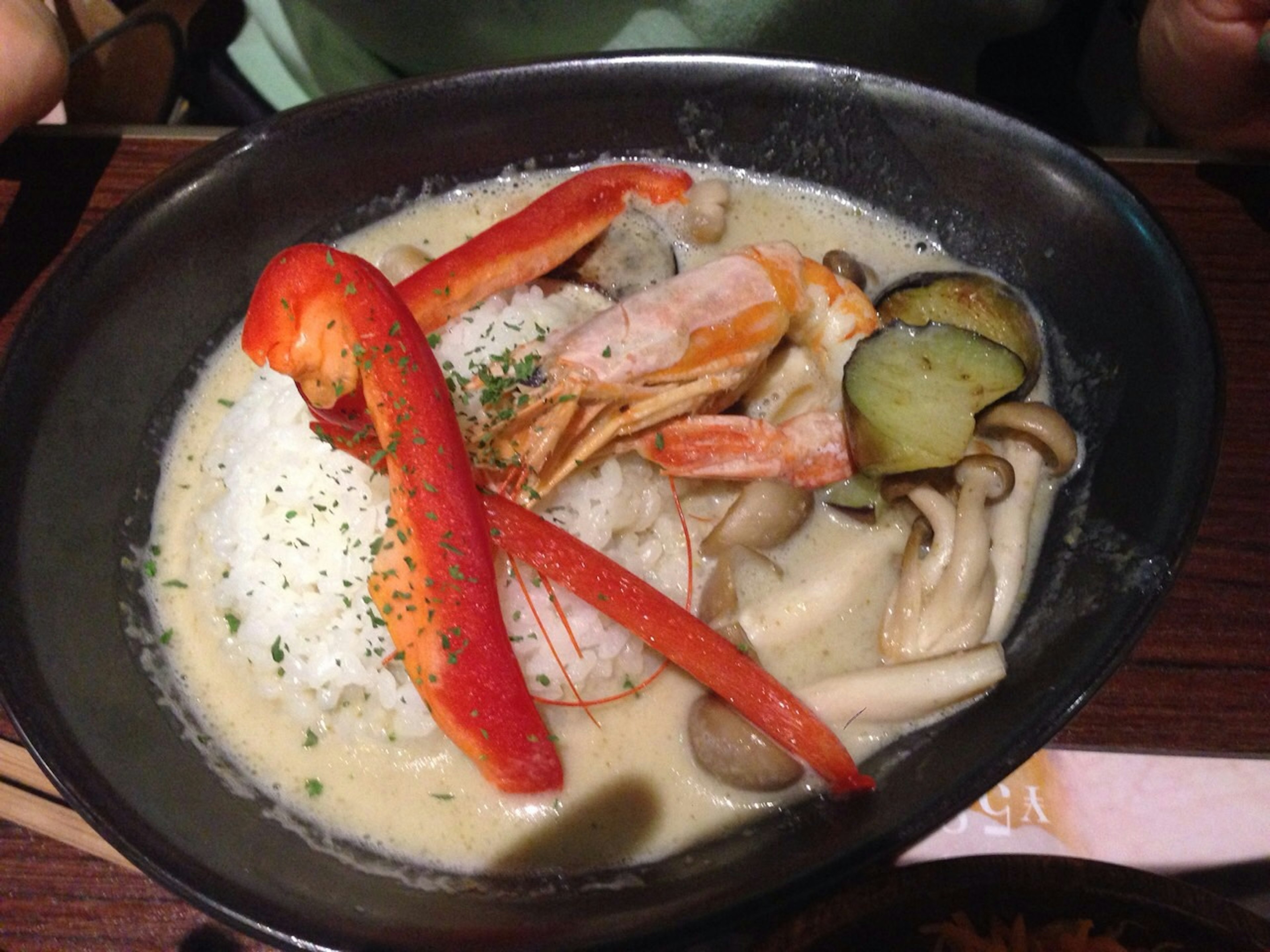 Un plato de sopa cremosa adornado con camarones y verduras