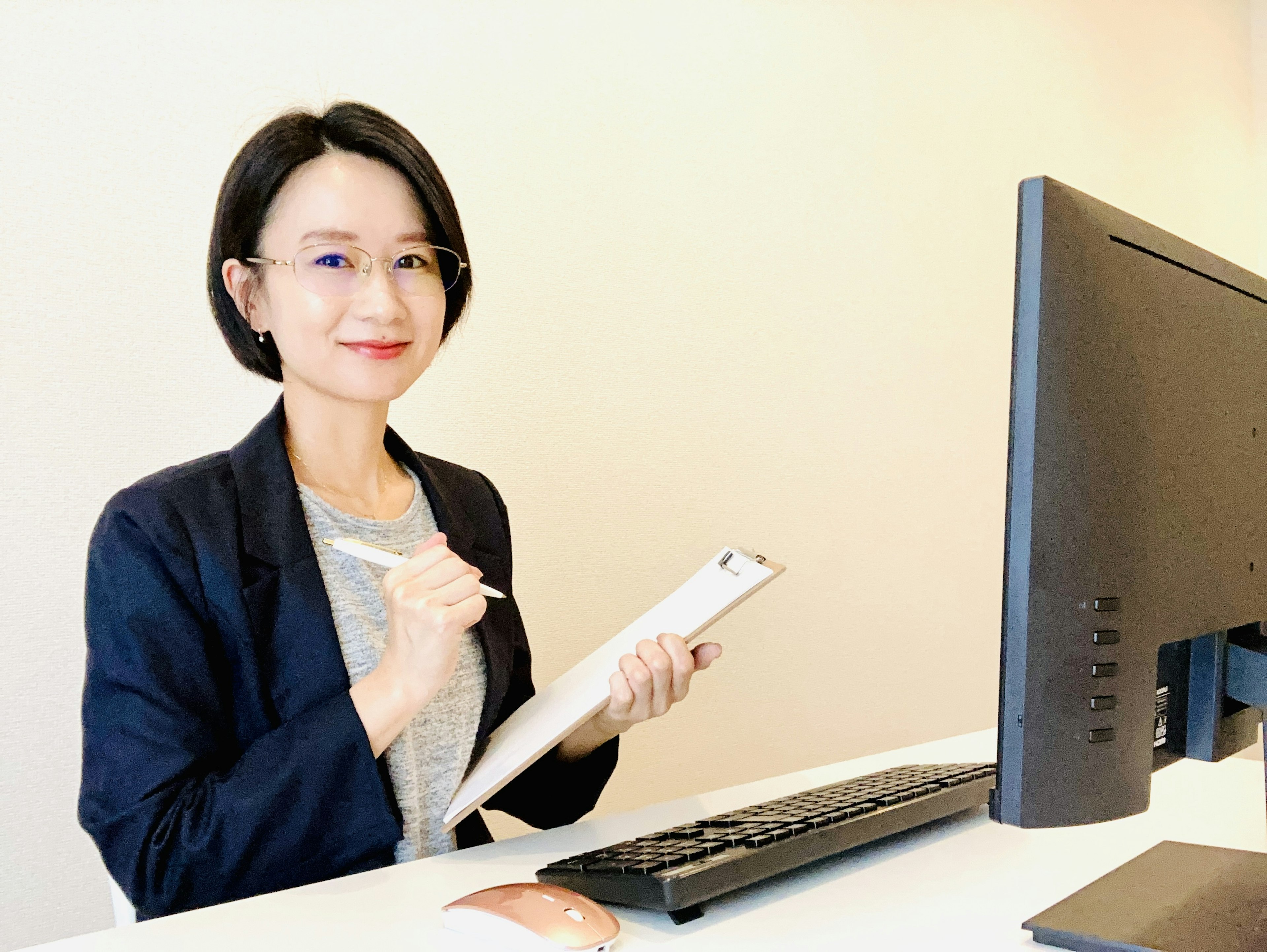 Businesswoman taking notes at a desk with a computer