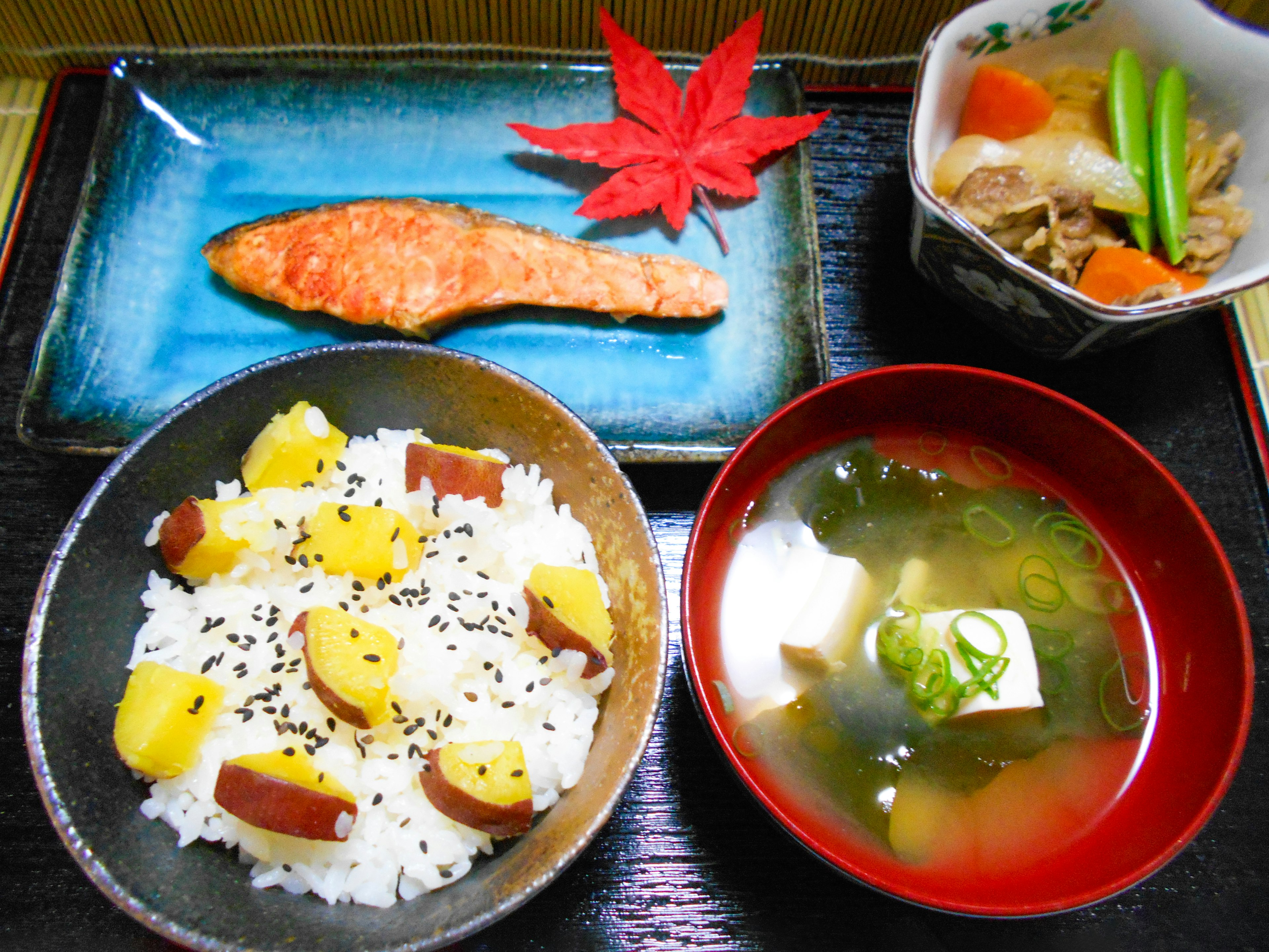 美麗的日本餐點，包括鮭魚、楓葉、紅薯飯、味噌湯和燉菜