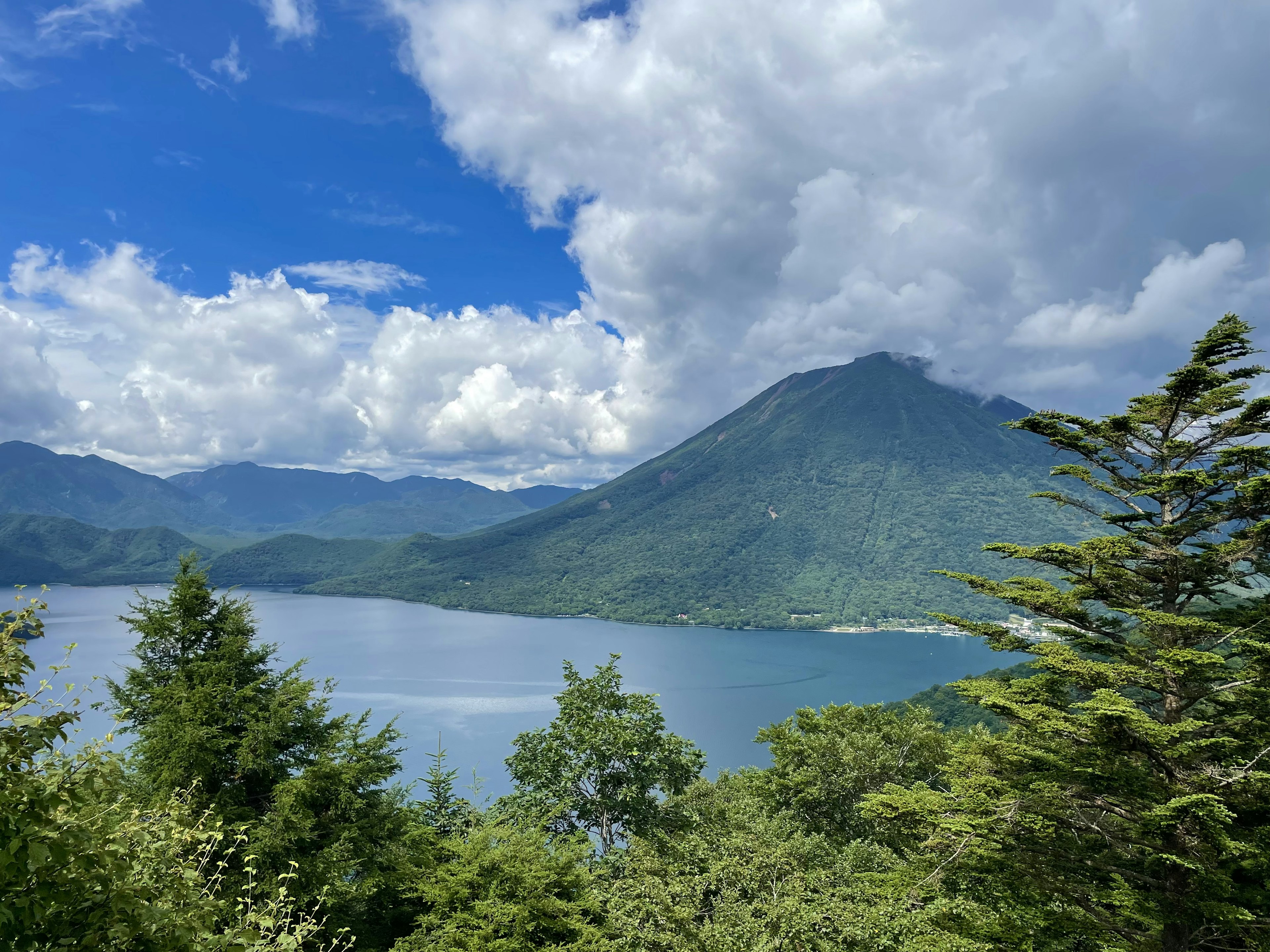 Vista escénica de un lago rodeado de montañas con cielo azul y nubes blancas