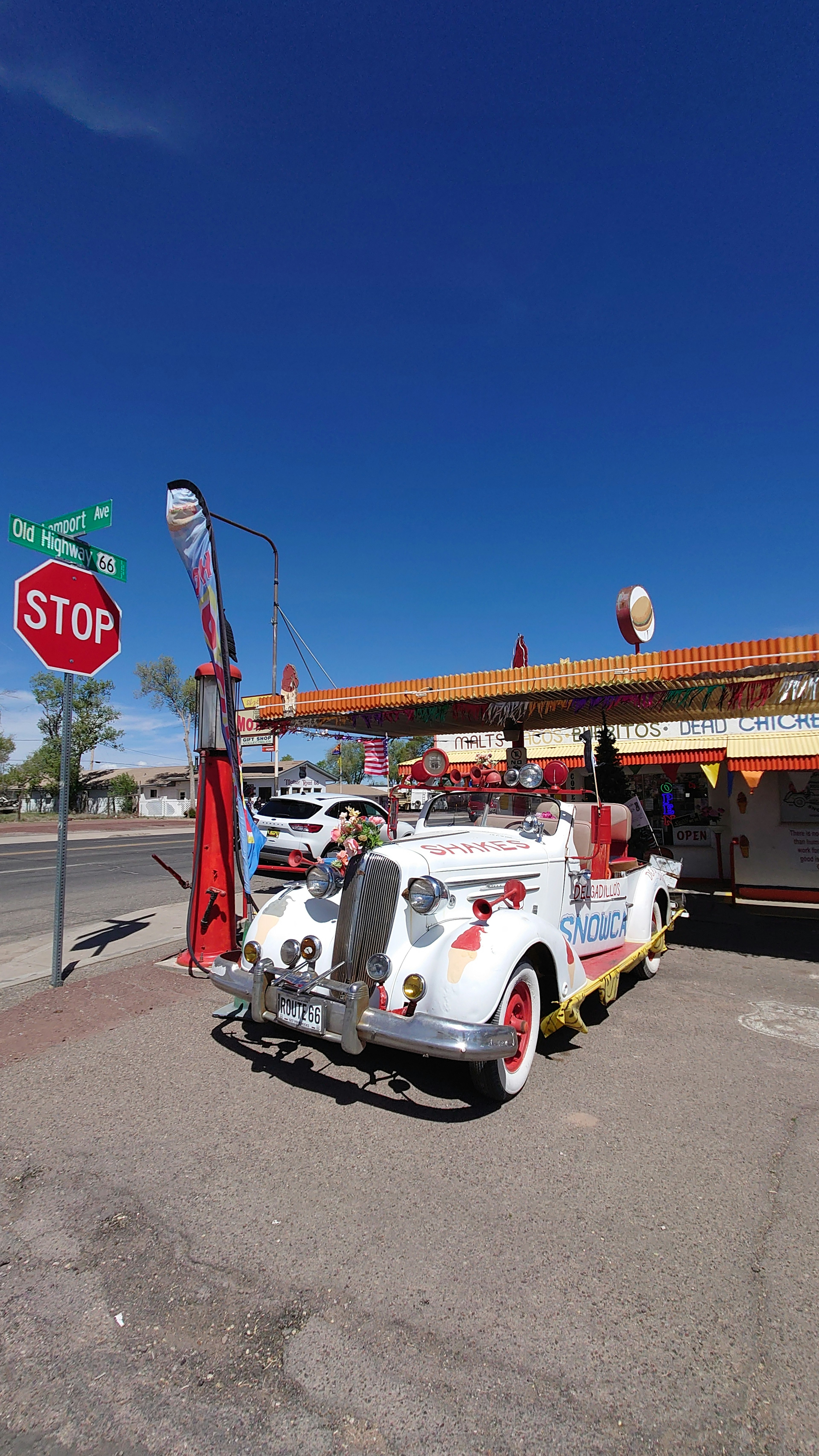 Auto d'epoca bianca con dettagli colorati vicino a un segnale di stop