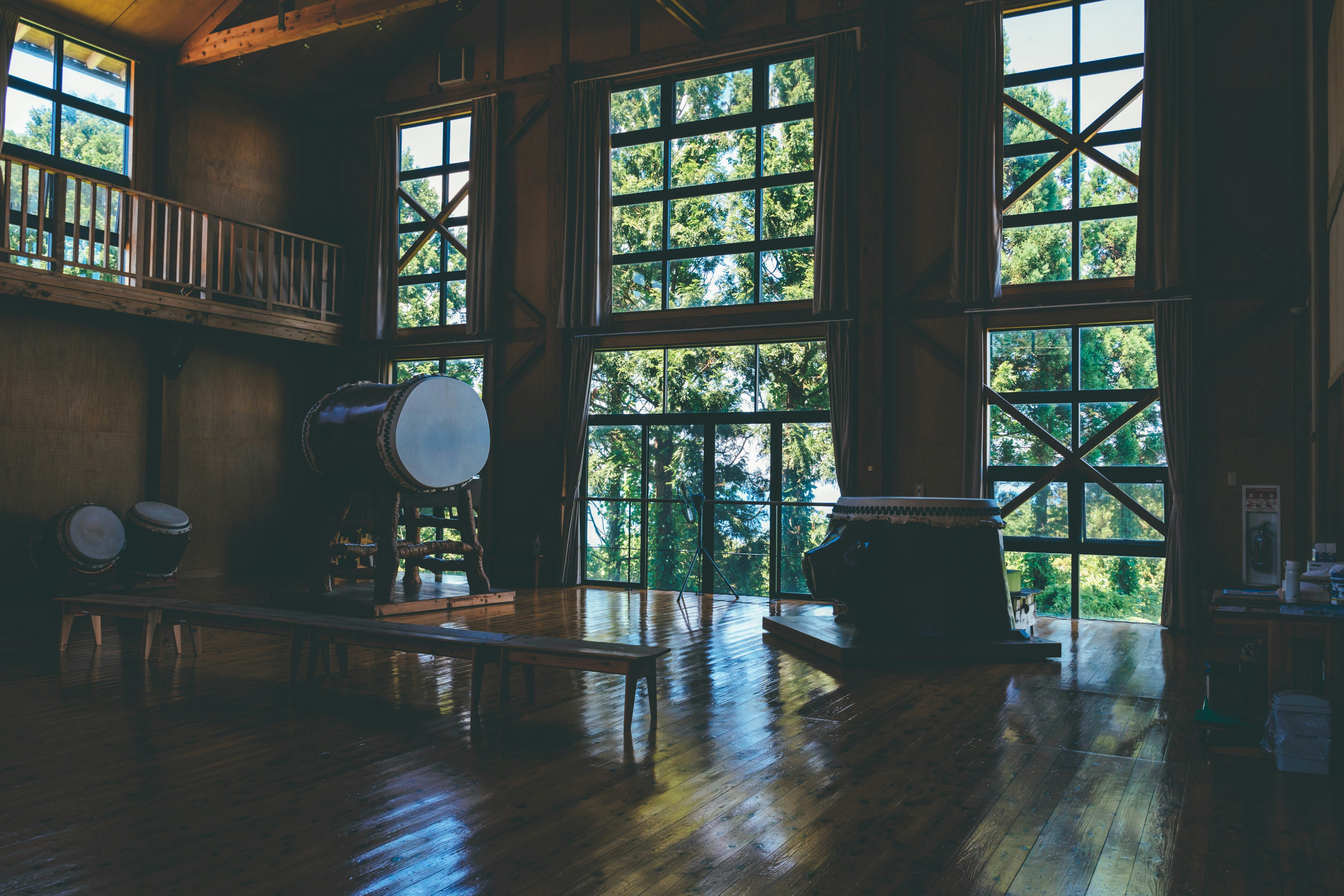 Spacious wooden interior with large windows showcasing green scenery