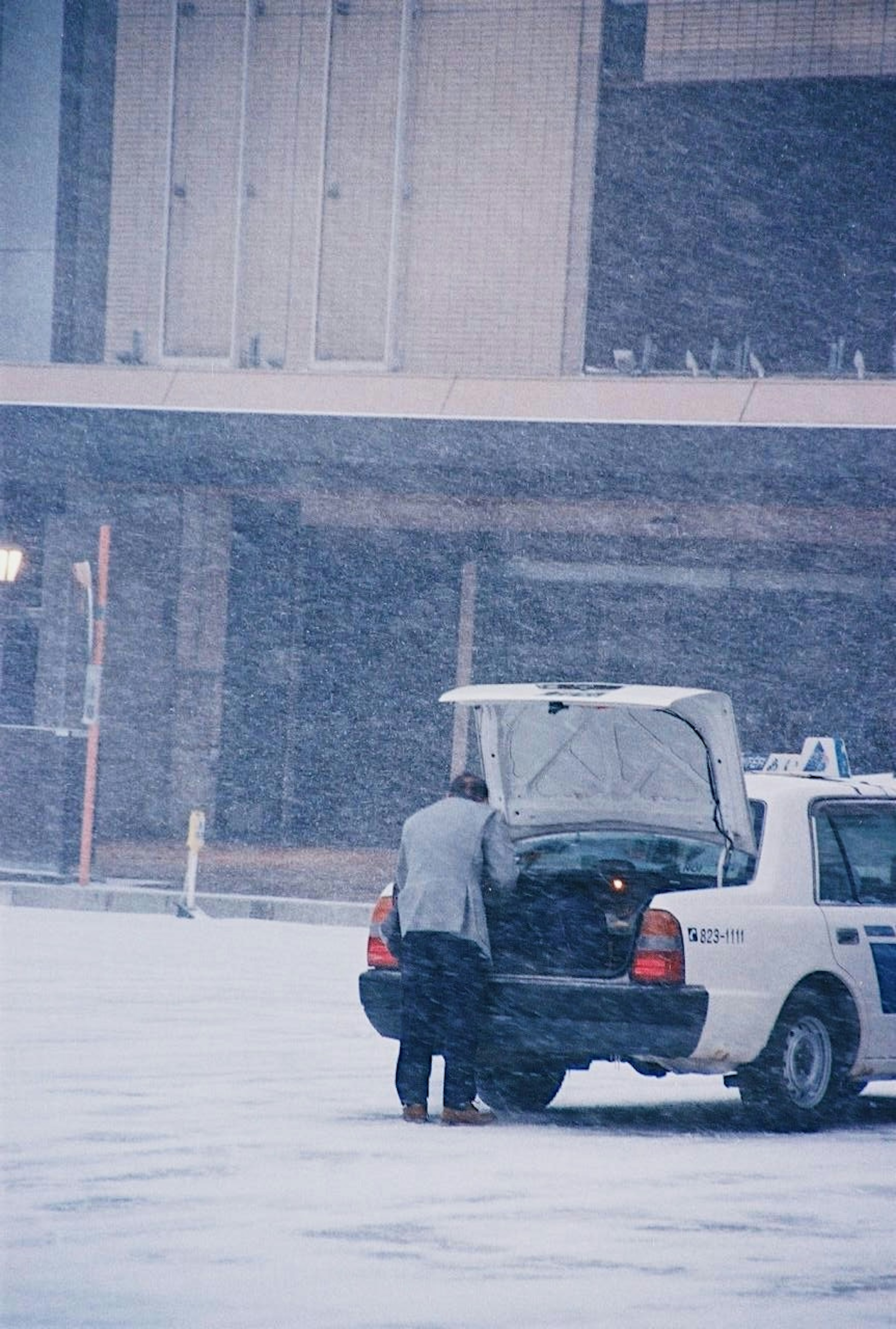 雪の中でタクシーのトランクを開ける男性