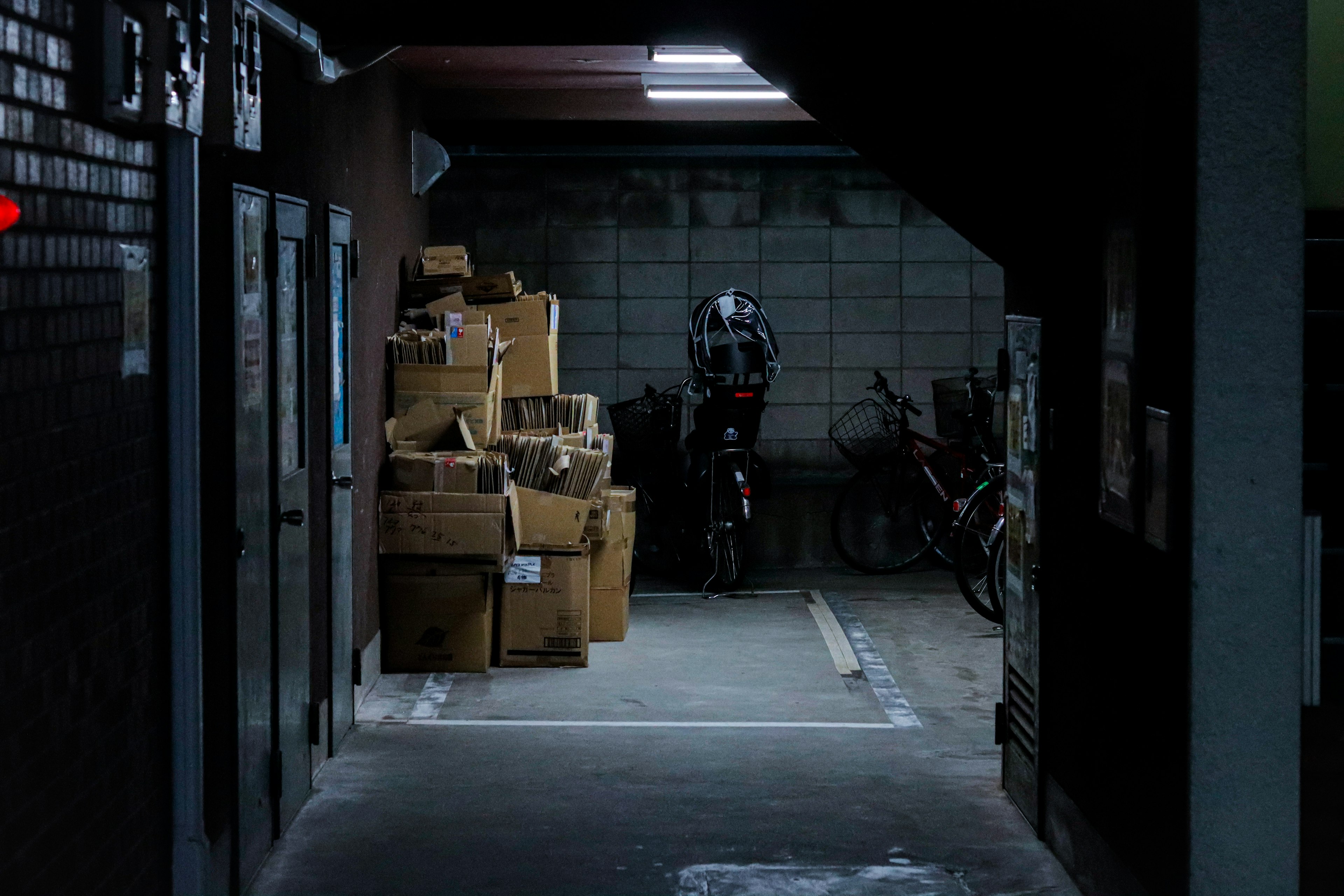 Pasillo débilmente iluminado con cajas apiladas y bicicletas