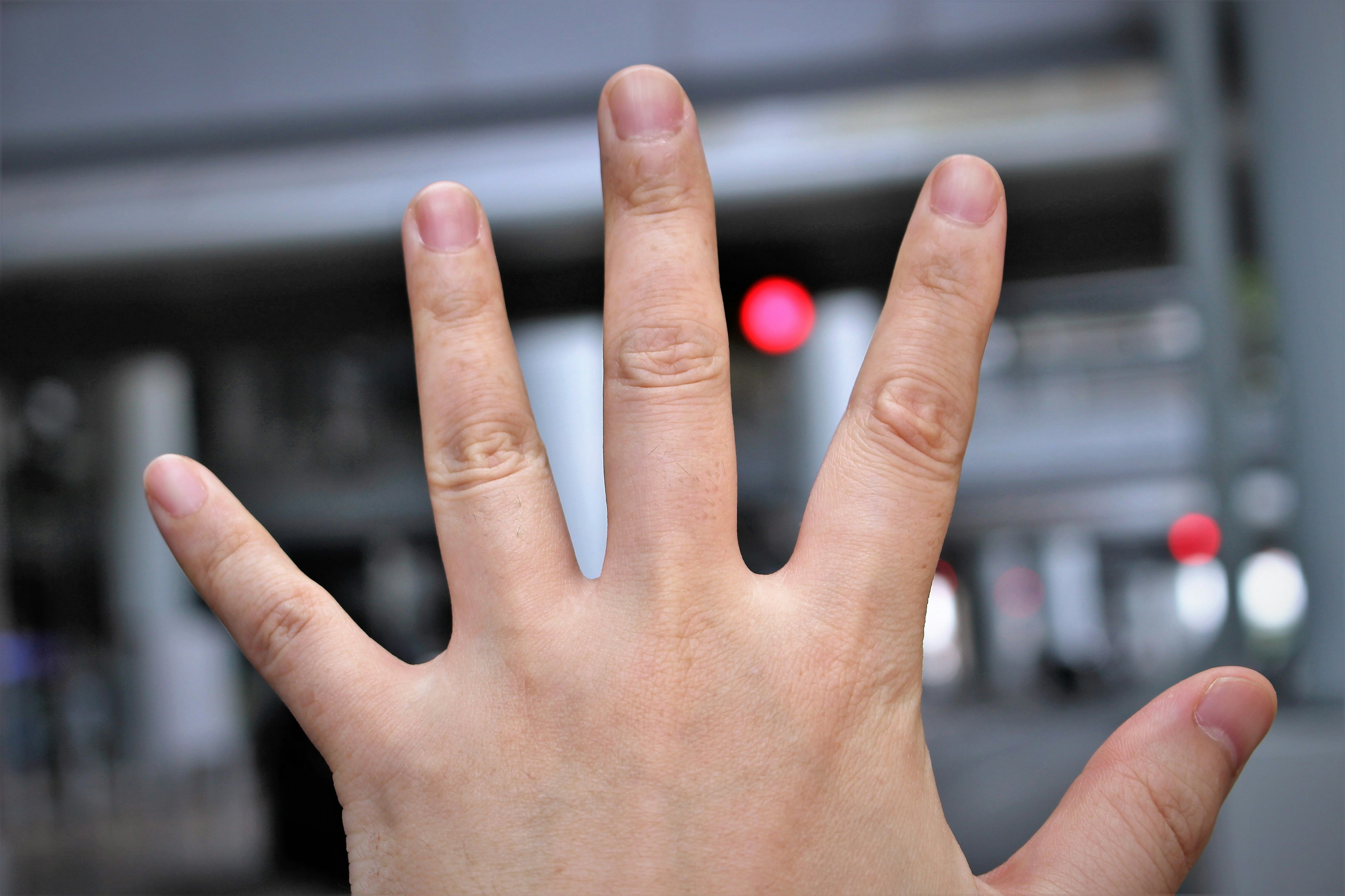 A hand with palm facing up showing fingers with a blurred red light in the background