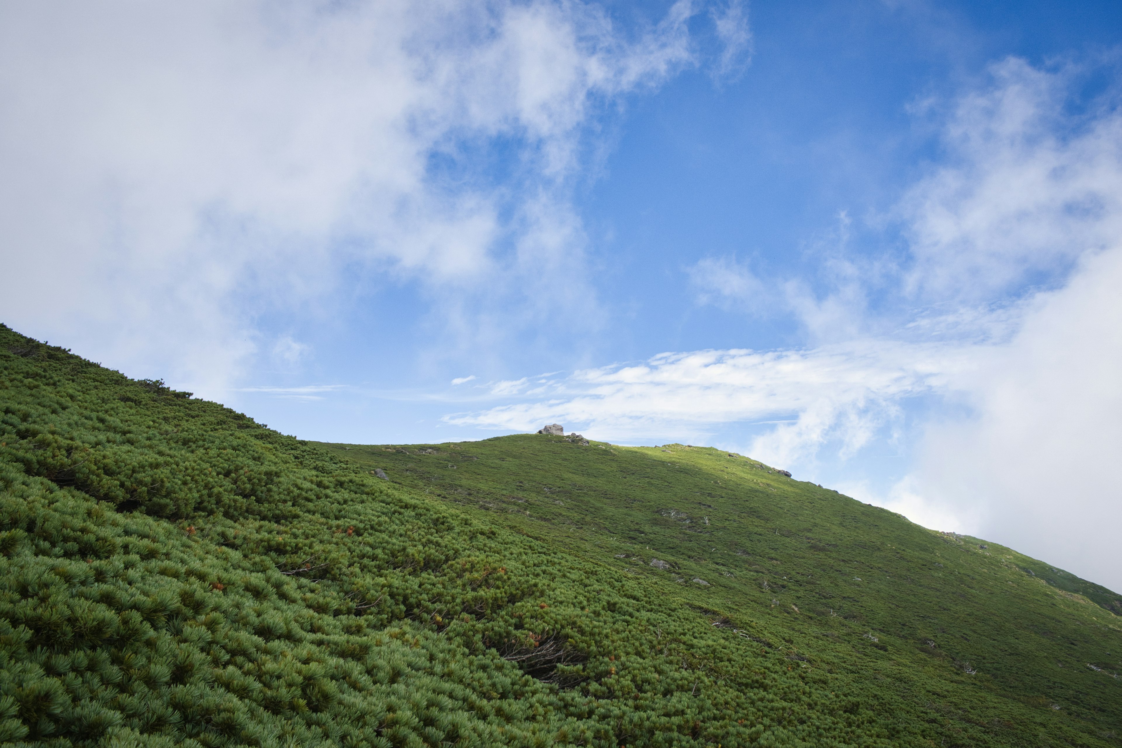 A scenic view of green hills under a blue sky with clouds