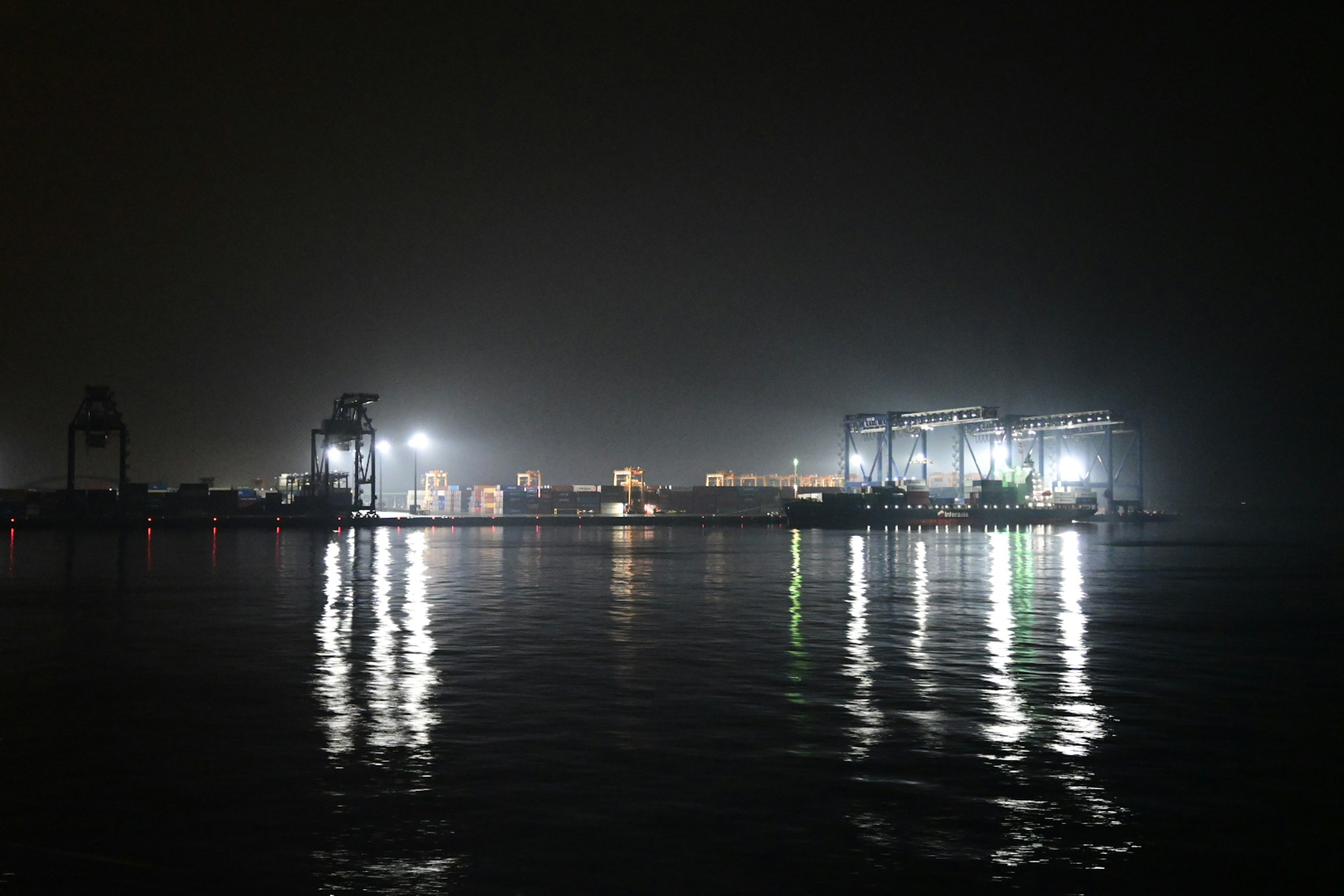 Vista nocturna de un puerto con luces reflejadas en el agua