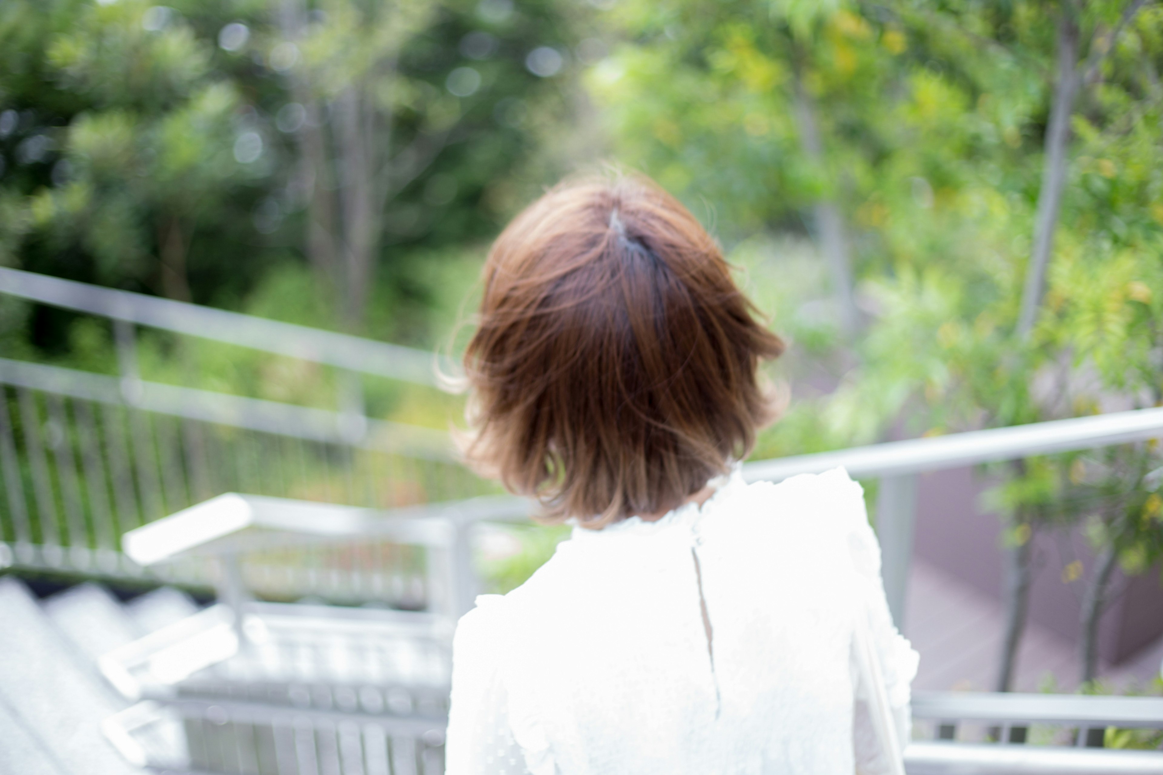 A woman seen from behind walking down stairs in a green outdoor setting