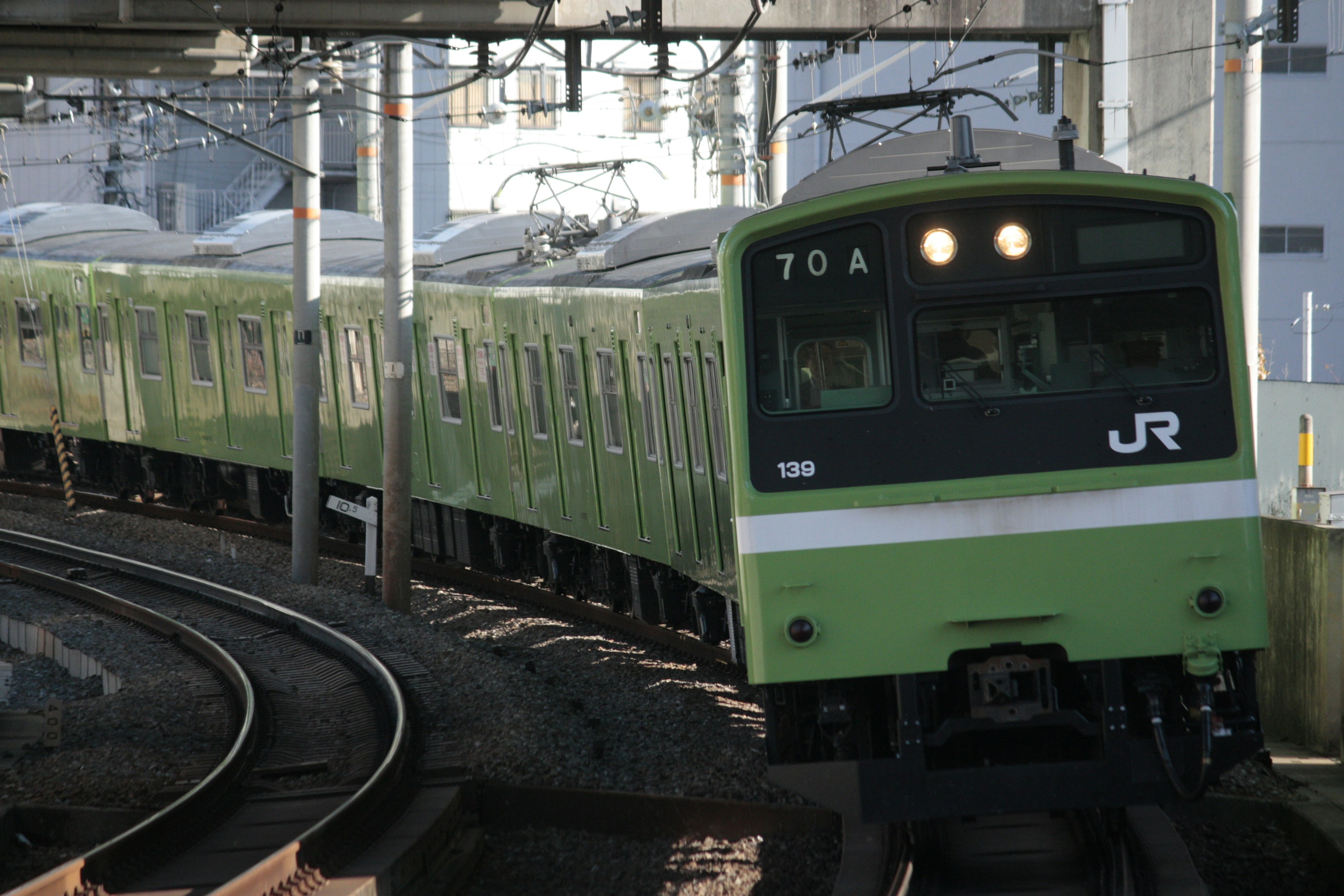 Tren verde JR girando en las vías