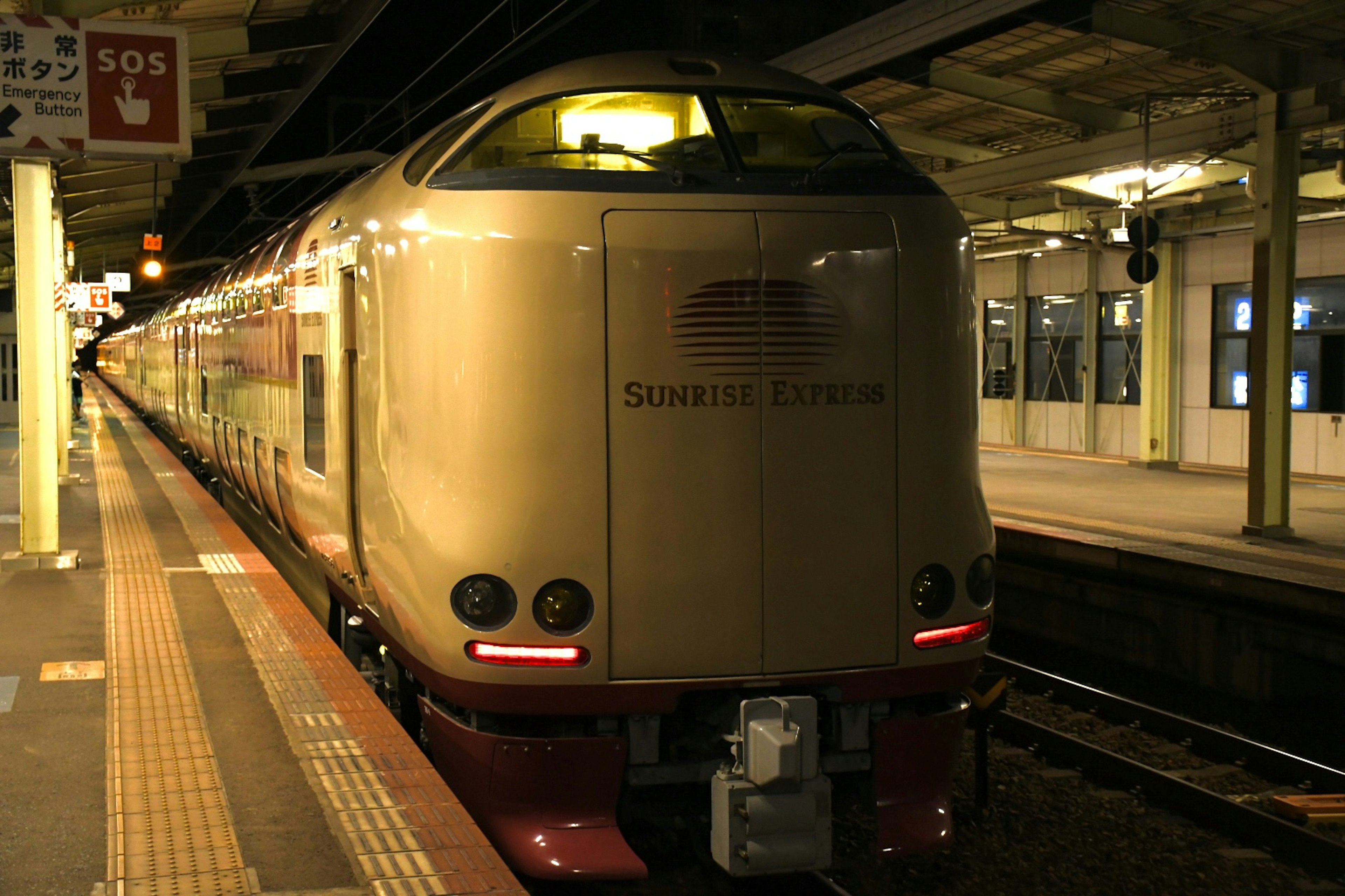 Rear view of a Shinkansen train at a station featuring a futuristic design and gold exterior