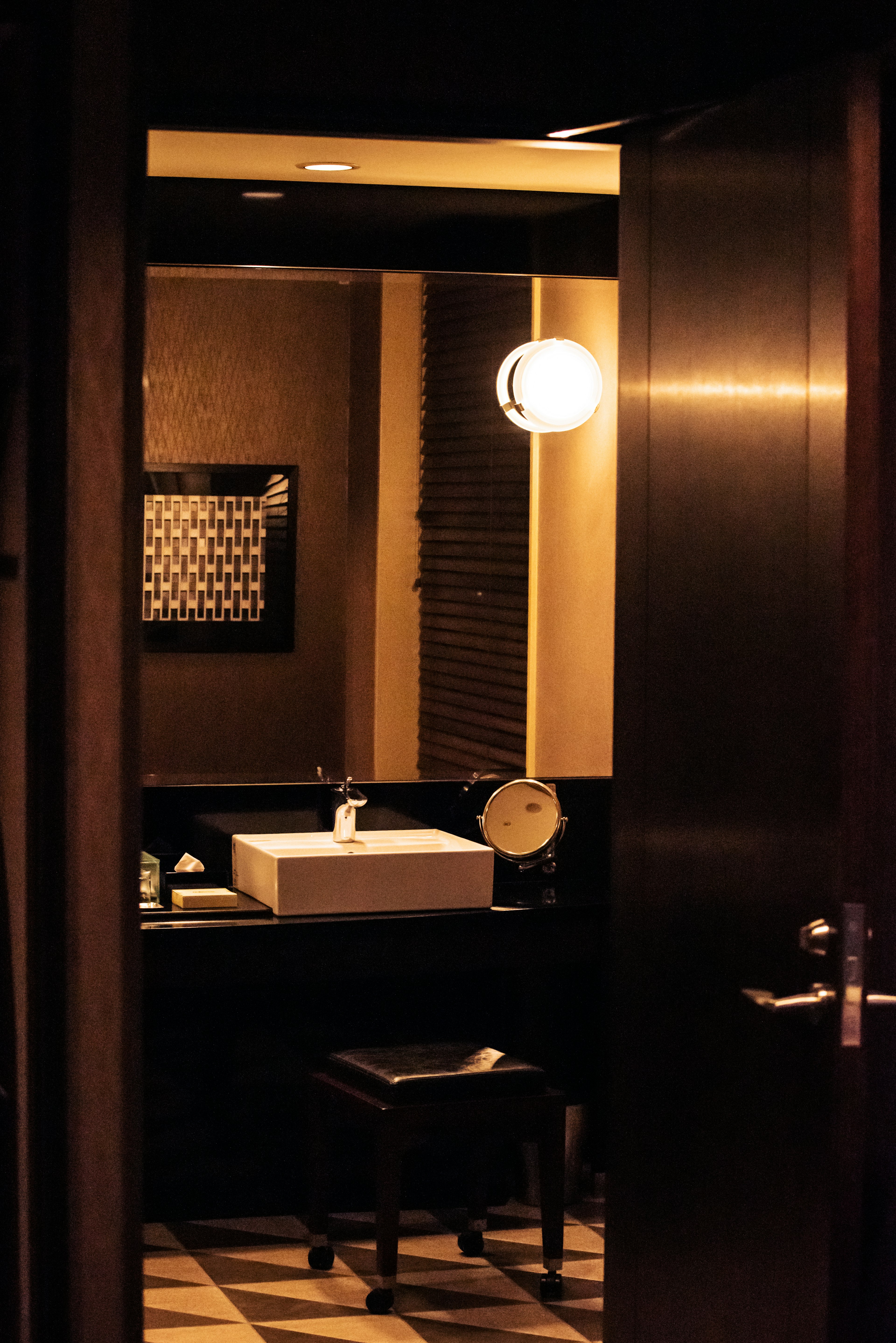 Image montrant l'intérieur d'une salle de bain faiblement éclairée avec un lavabo et une chaise