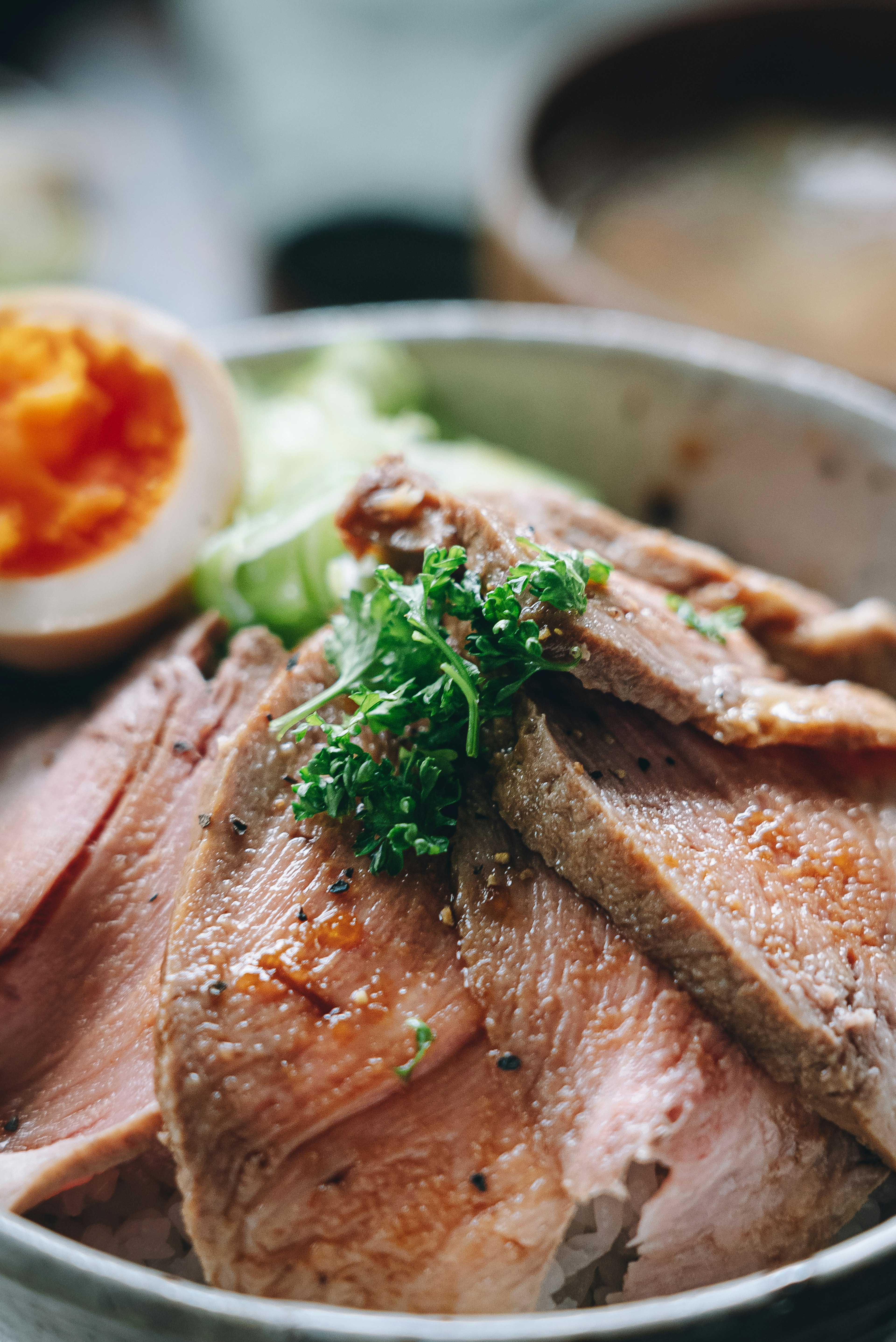 Delicious slices of meat garnished with fresh herbs and a soft boiled egg