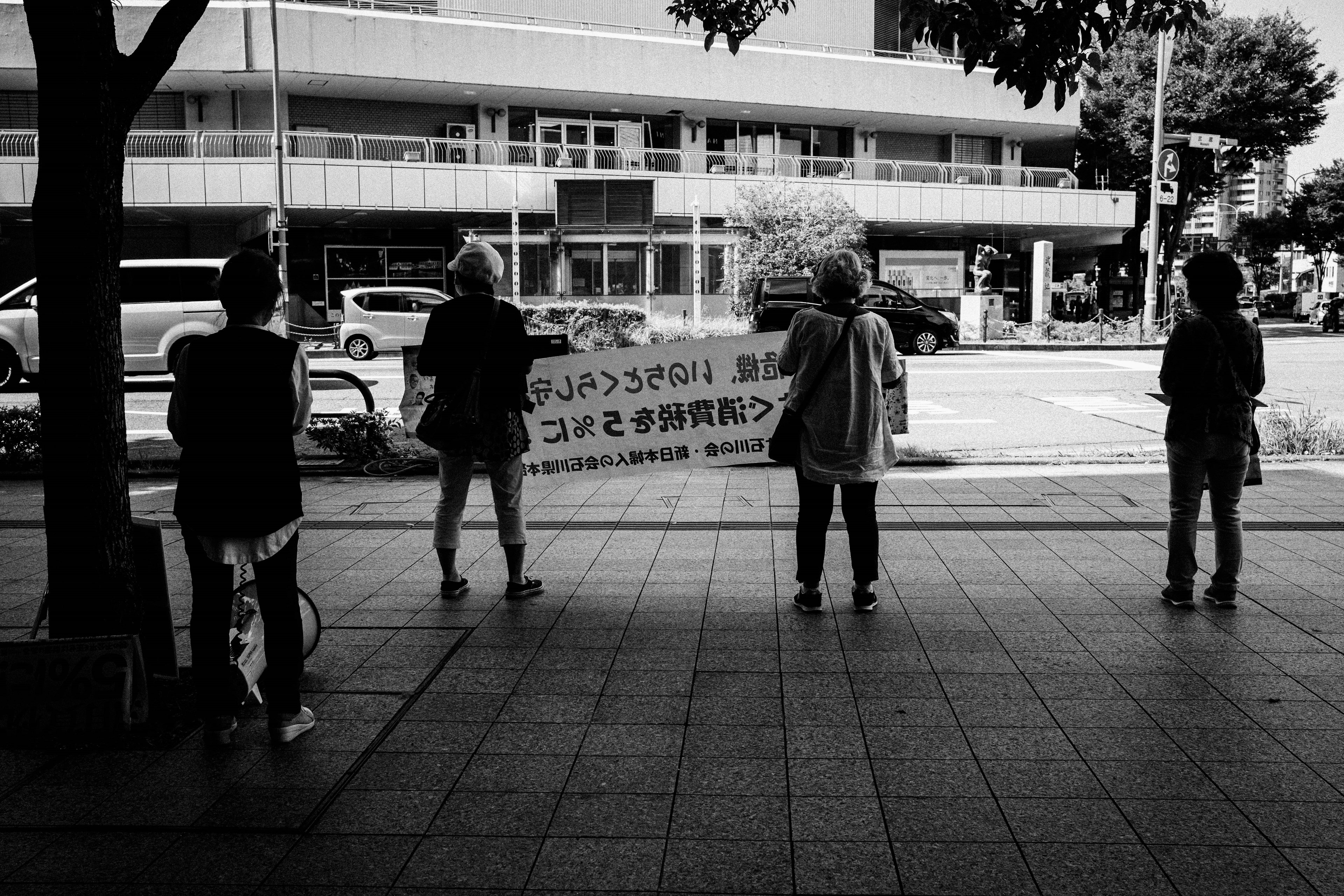 Black and white photo of people holding a large banner