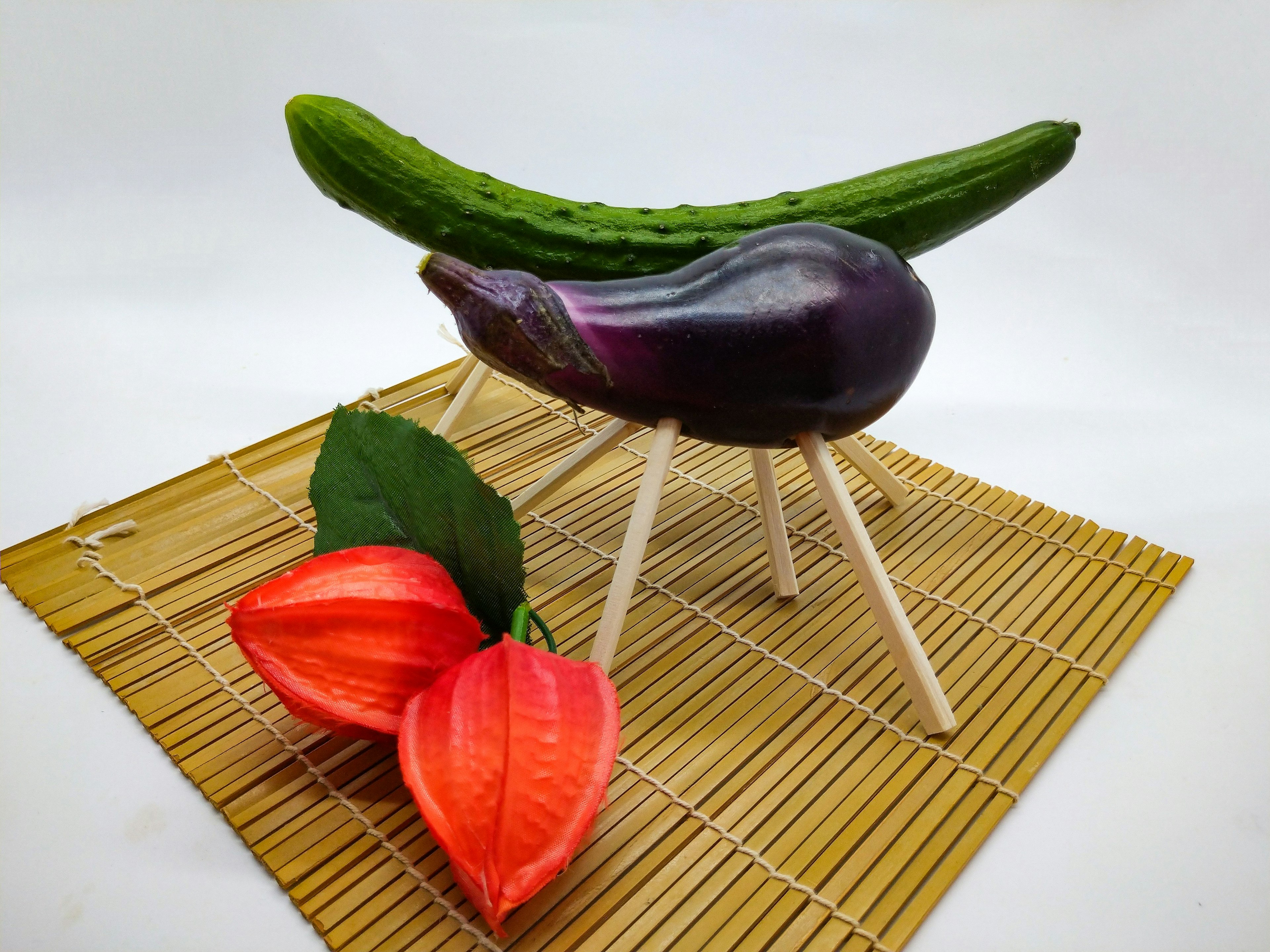 Unique art piece featuring an eggplant and cucumber on a bamboo mat