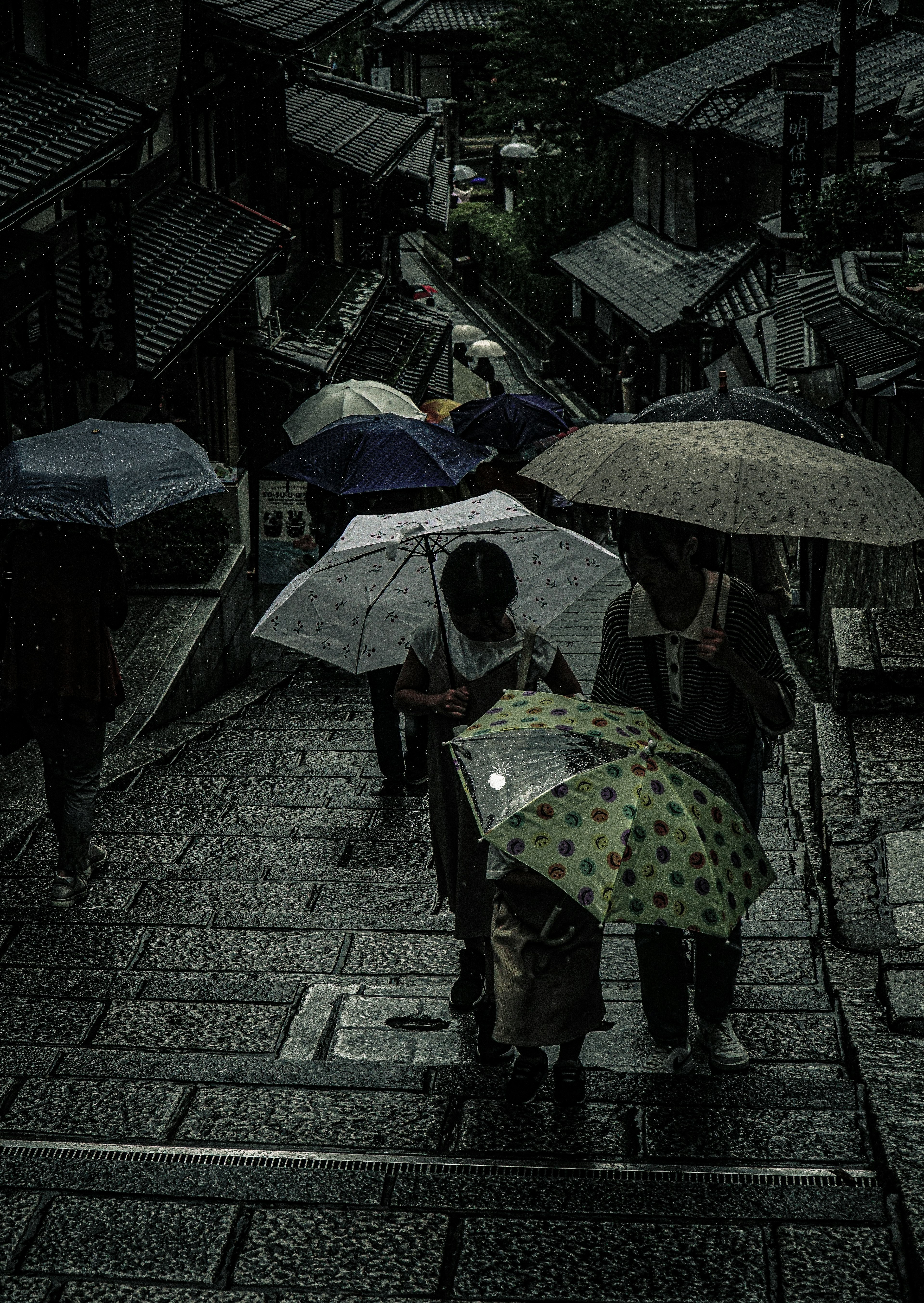 人們在雨中走，手持彩色雨傘，古老街道