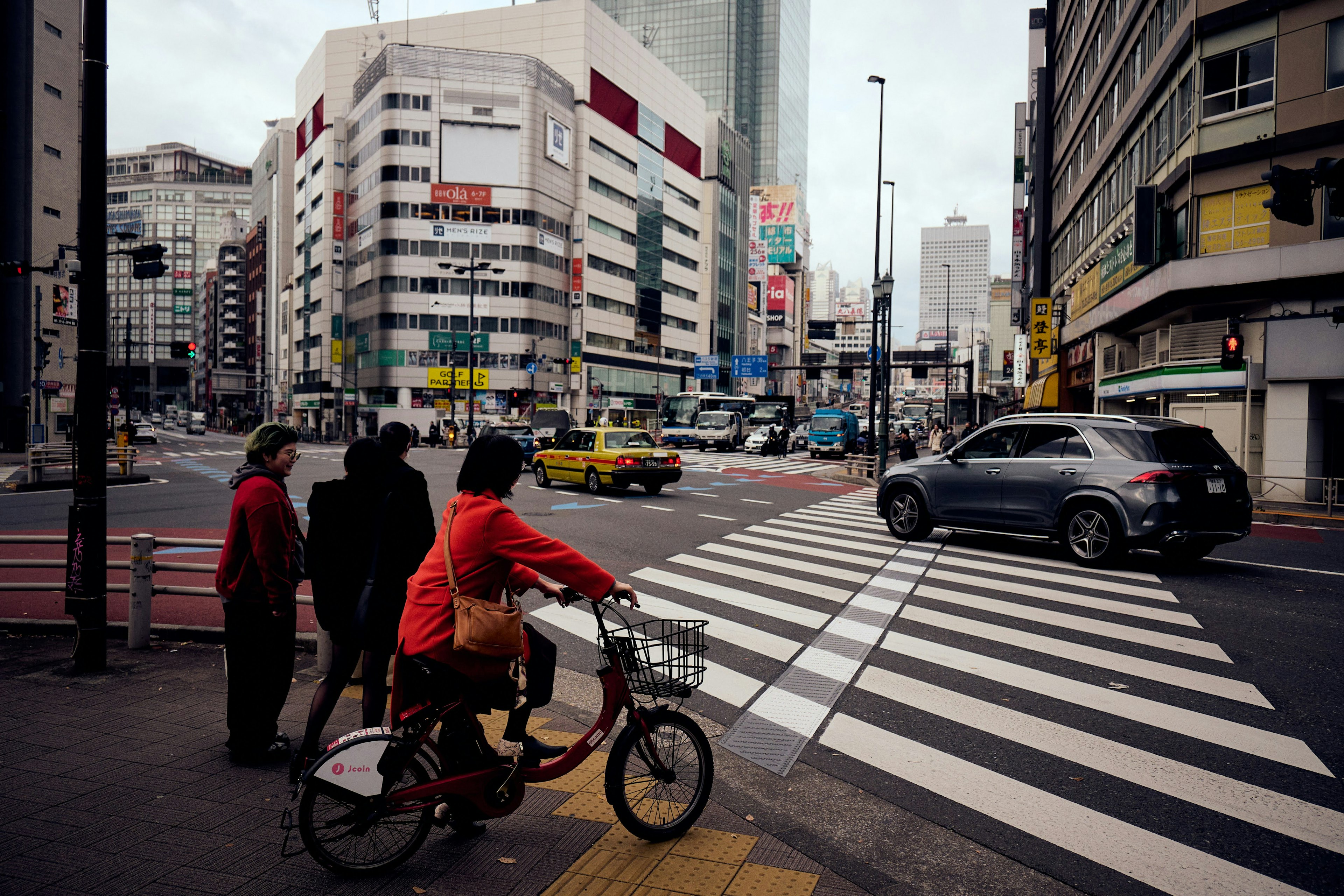 都市の交差点で自転車に乗る人と信号待ちの人々