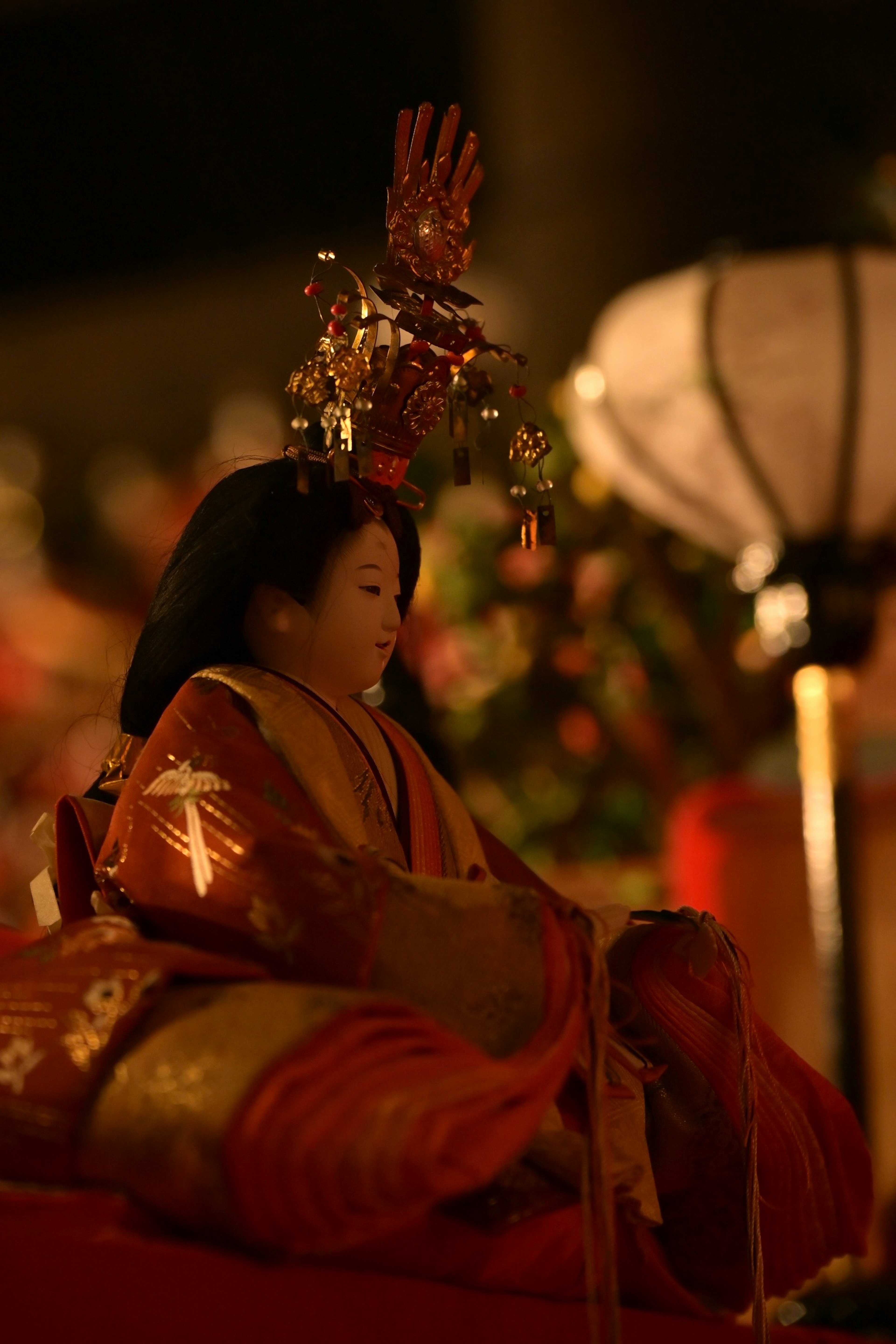 A beautifully adorned doll seated at a night festival