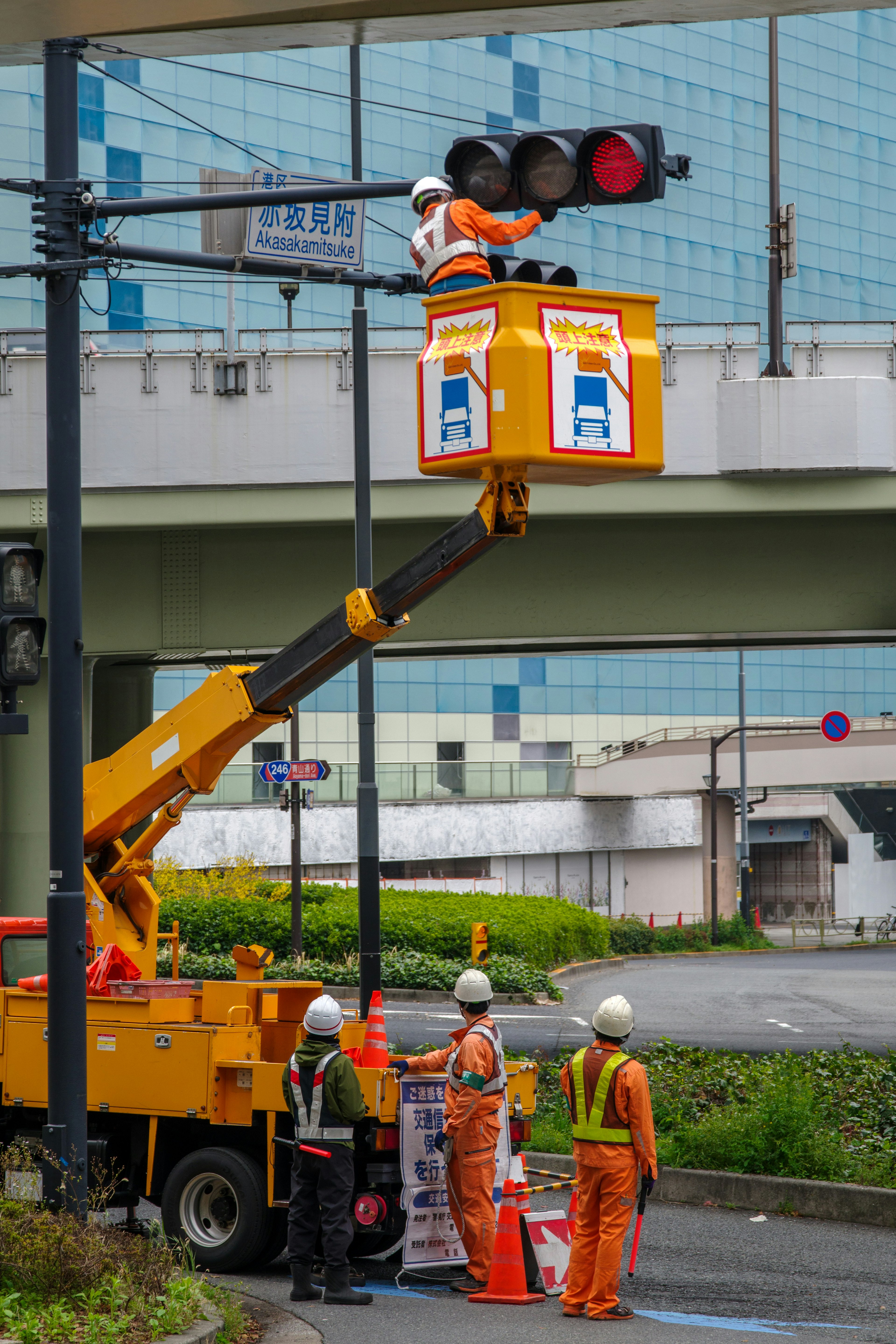 Workers repairing a traffic light using a crane vehicle