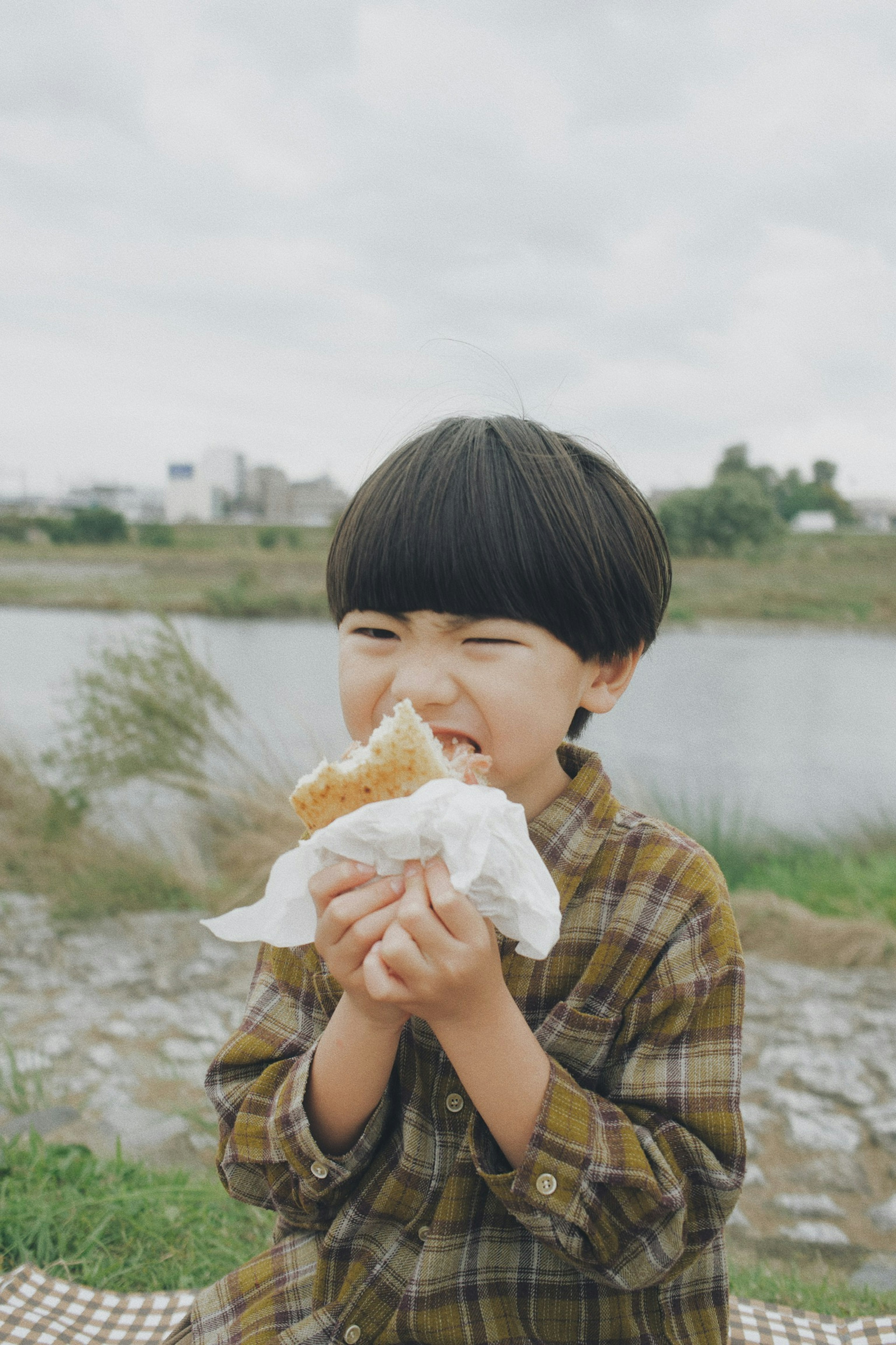 Junge genießt einen Snack im Park Lächelt beim Essen von Brot Umgeben von Natur